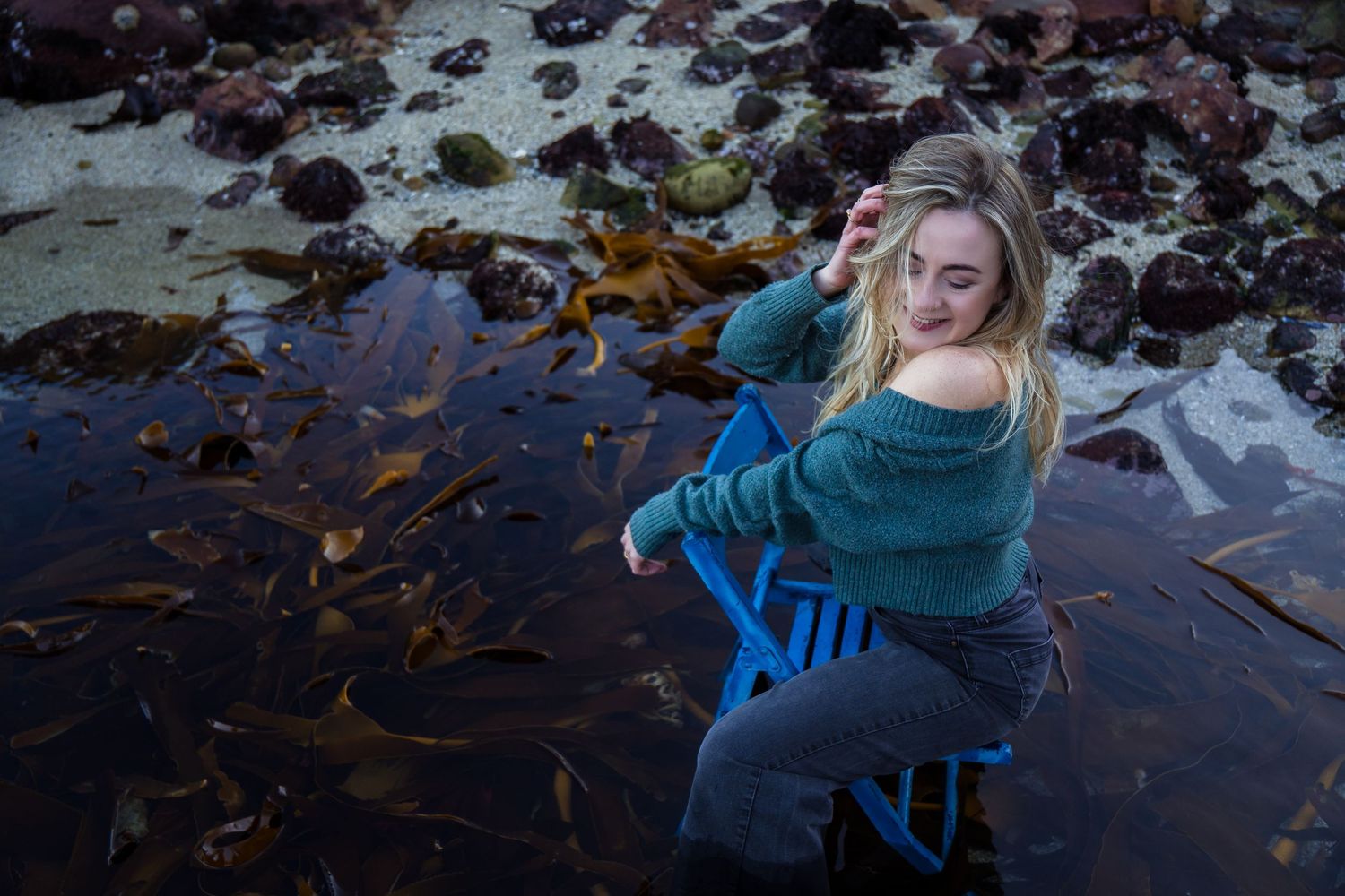 Outdoor lifestyle portrait of a woman among coastal rocks and tidal pools, photographed in Cape Town, South Africa.