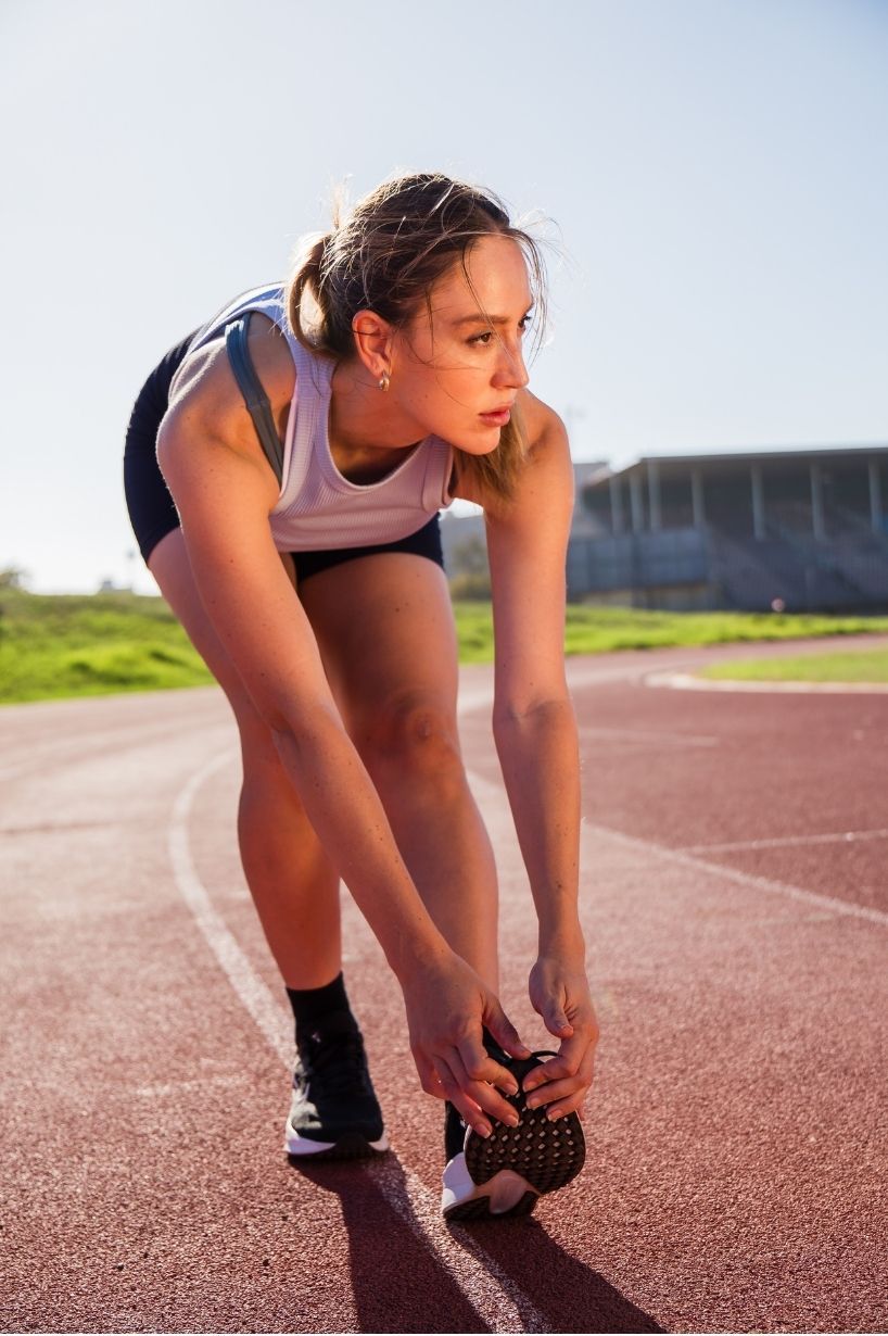 Female runner preparing on an athletics track, captured through professional sports and fitness photography in Cape Town.