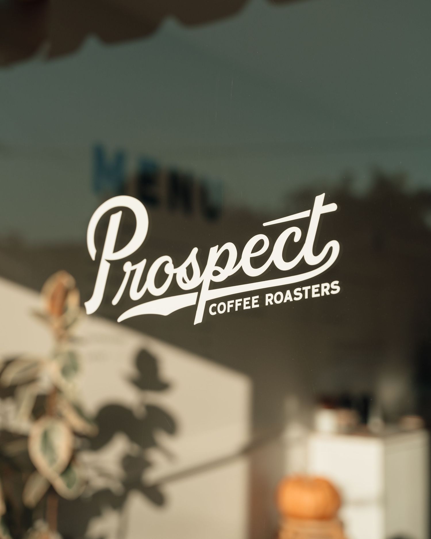 Prospect Coffee Roasters logo displayed on storefront window with soft natural light reflection.
