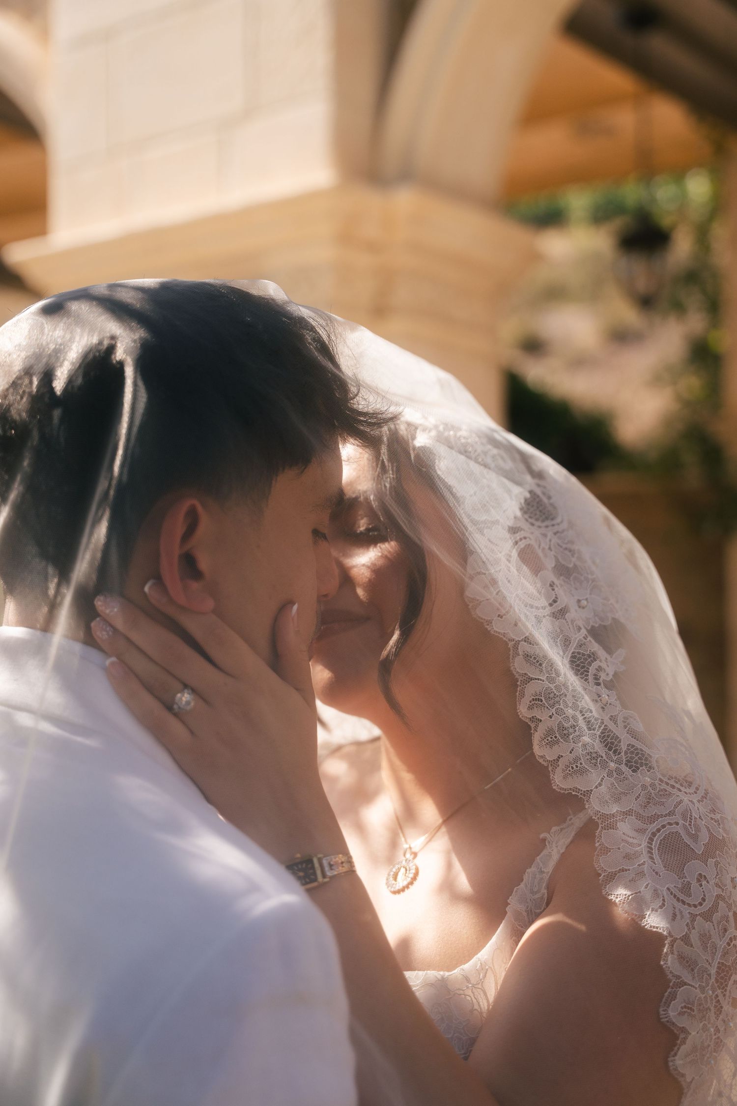 Bride and groom, Emmanuel Pacquiao and wife Carolina Pimentel Pacquiao, share romantic kiss under lace wedding veil in warm sunlight.