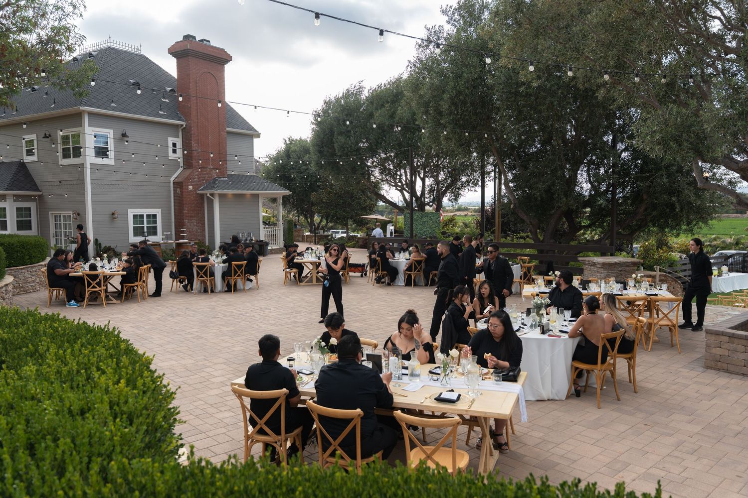 Aerial view of elegant outdoor wedding reception on stone patio with round tables.