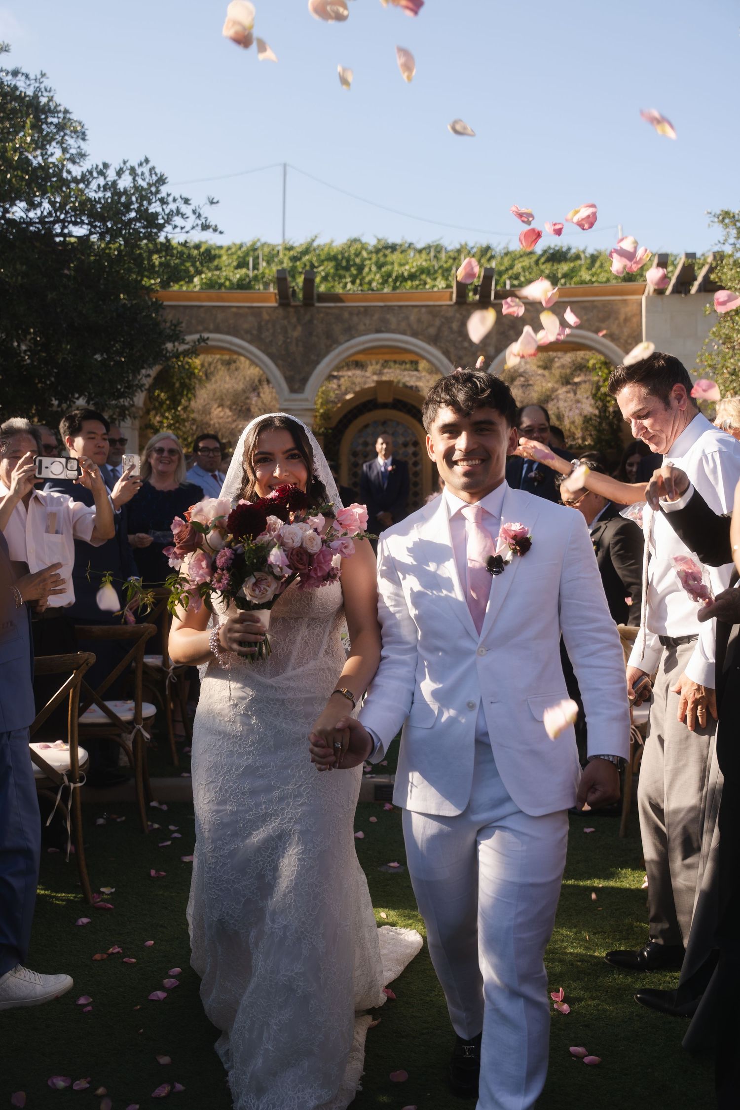Newlyweds Emmanuel Pacquiao and wife Carolina Pimentel Pacquiao exit ceremony as guests toss pink rose petals in a garden wedding venue.