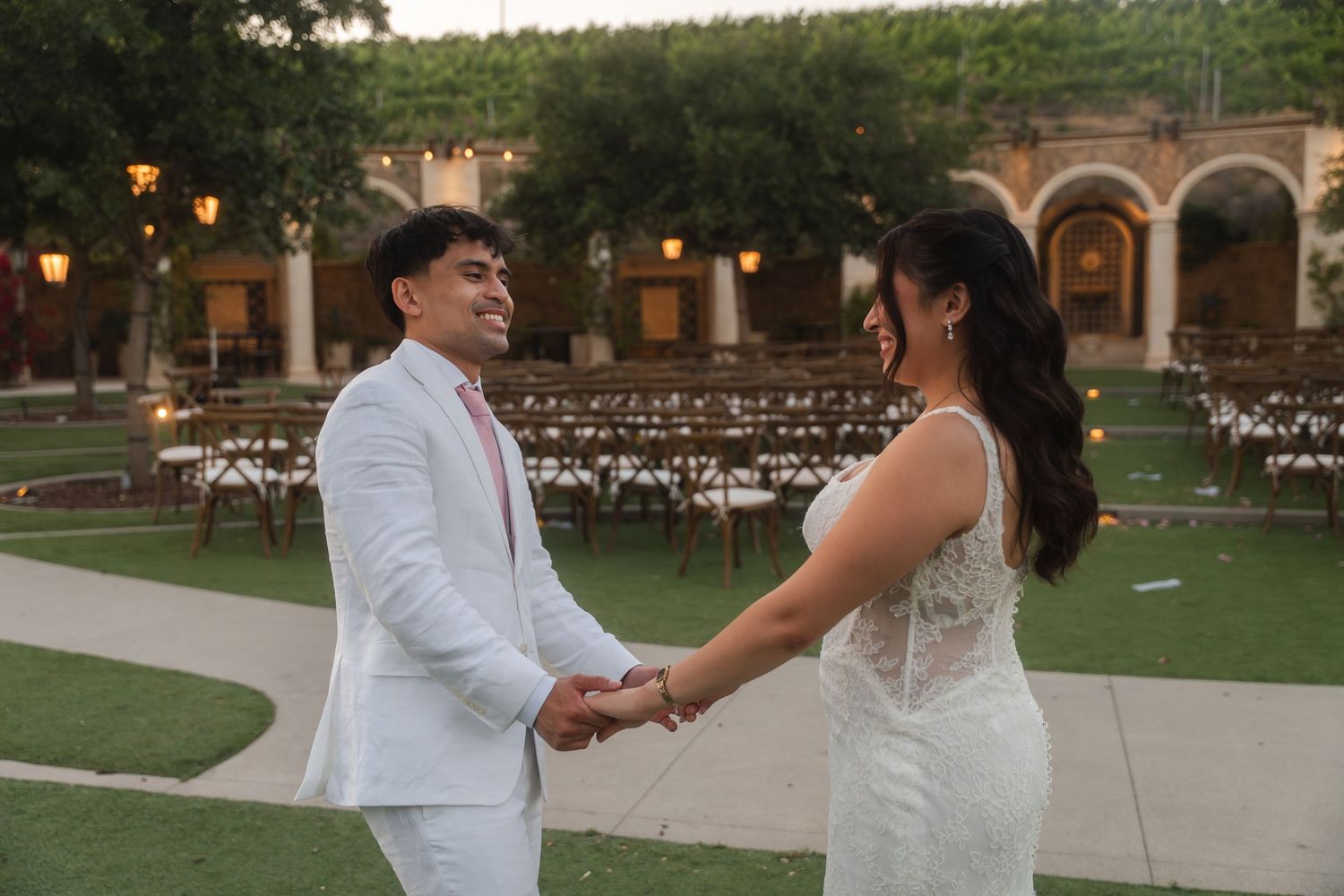 Bride and groom, Jimuel Pacquiao and Carolina Pacquiao holding hands and smiling at each other during outdoor wedding ceremony.