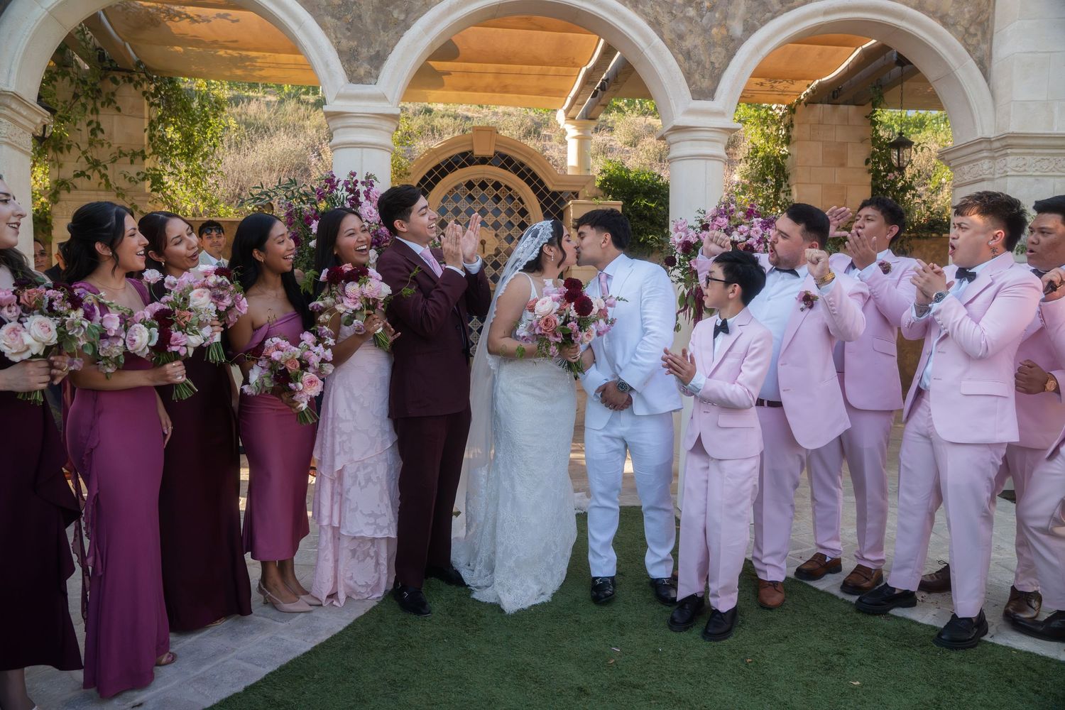 Emmanuel Pacquiao and wife Carolina Pimentel Pacquiao. Wedding party in pink and burgundy celebrating with couple during outdoor ceremony.