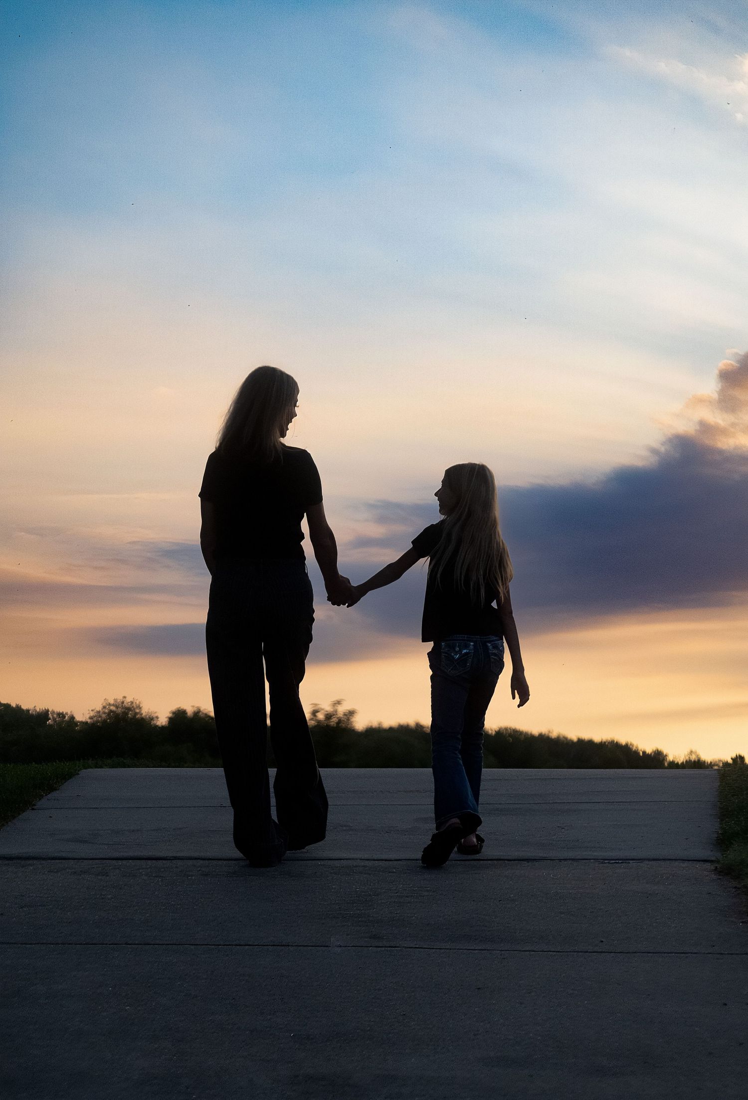 Mother and daughter walking together at sunset during a portrait session at Chalco Hills in Omaha