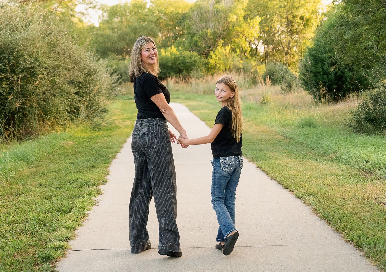 Candid mother and daughter walking and laughing during a portrait session at Chalco Hills in Omaha