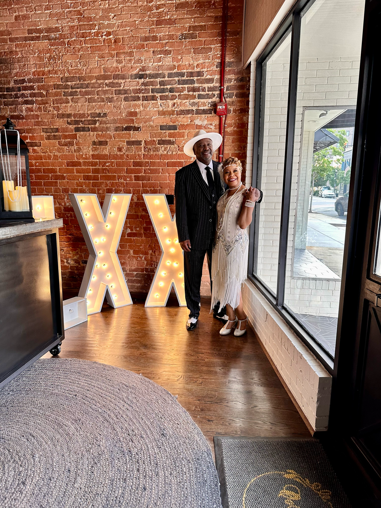 Large illuminated letters spell out 'XXII' against exposed brick wall in an indoor event space with natural lighting.