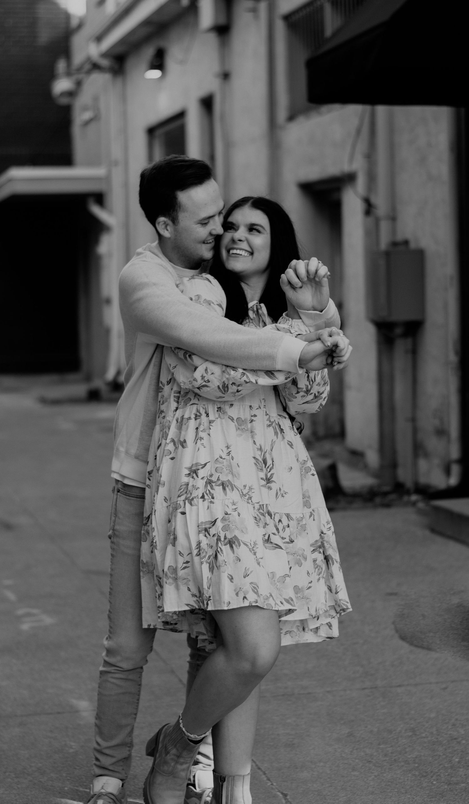 Playful black and white dance pose in an urban setting with floral dress.