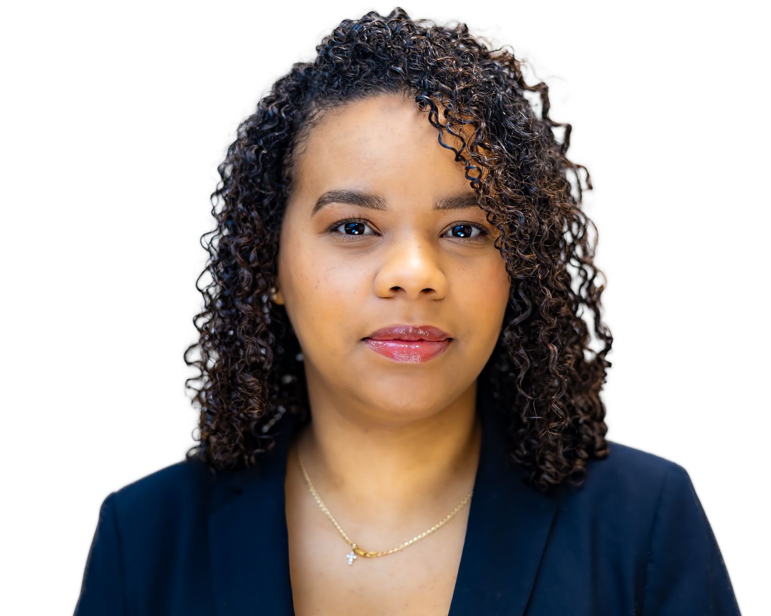 Professional businesswoman with curly hair wearing a navy blazer and delicate necklace against white background.