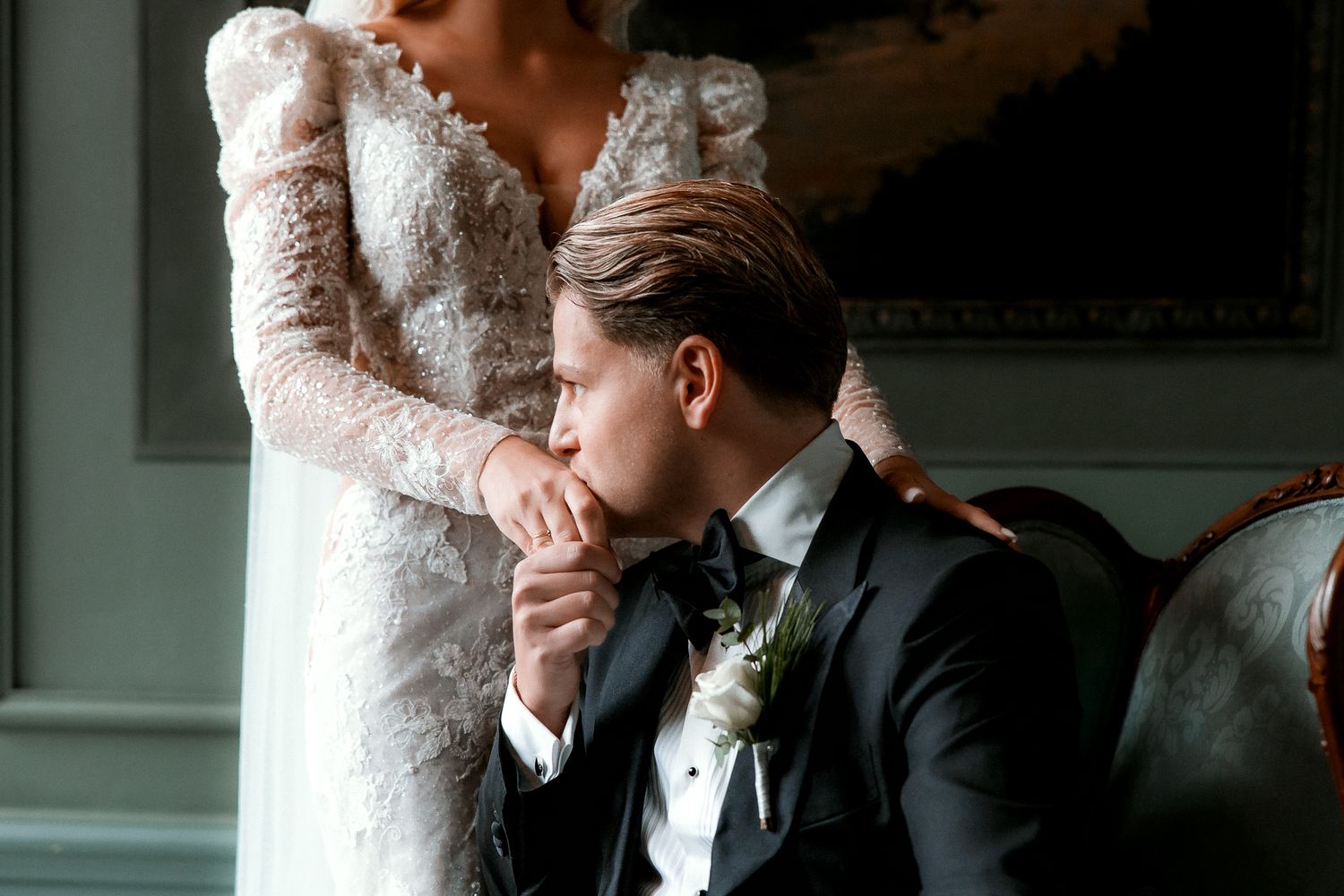 A tender intimate moment between a couple on their wedding day, with the groom kissing the bride's hand.
