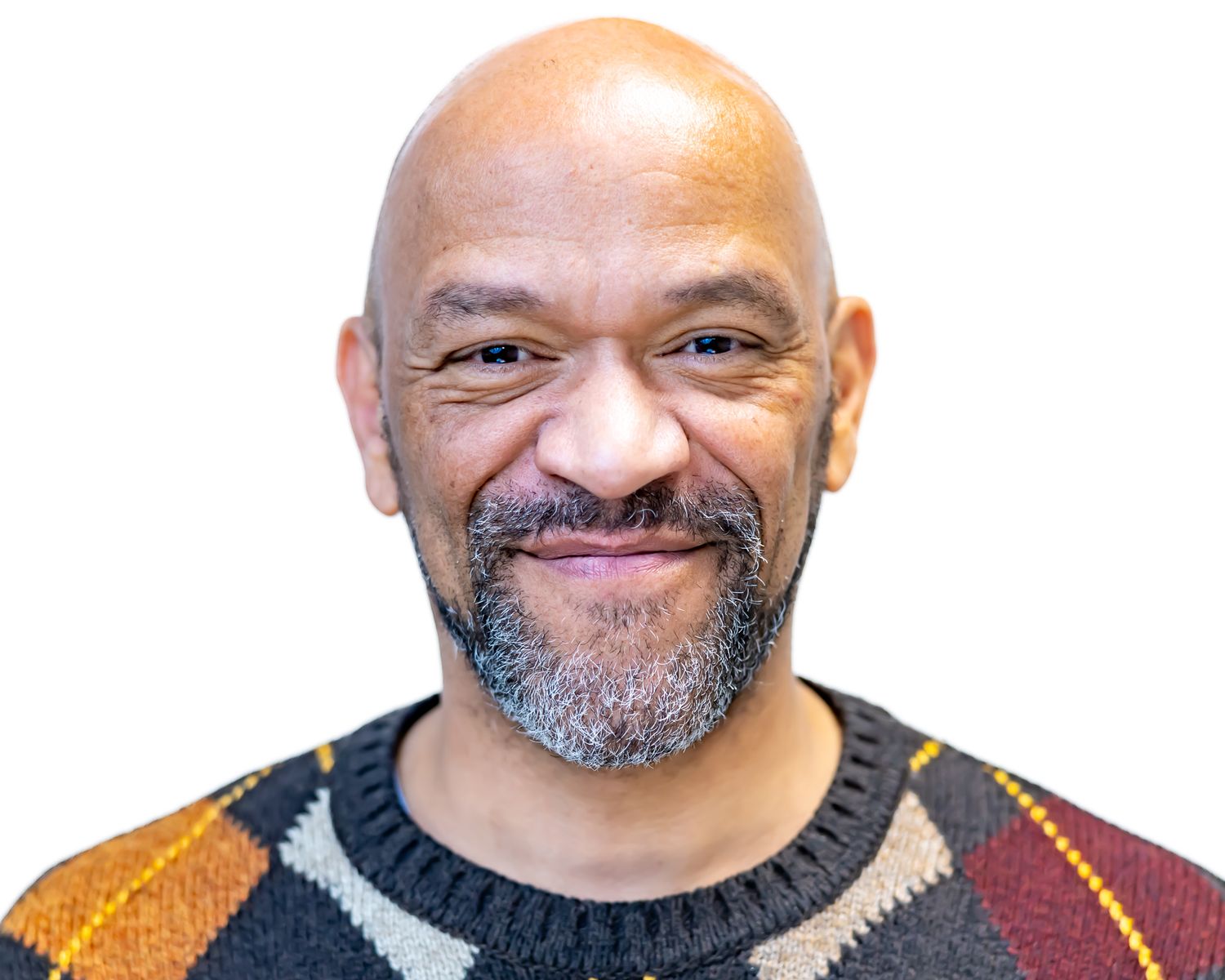 A person wearing a patterned sweater smiles warmly at the camera against a white background.