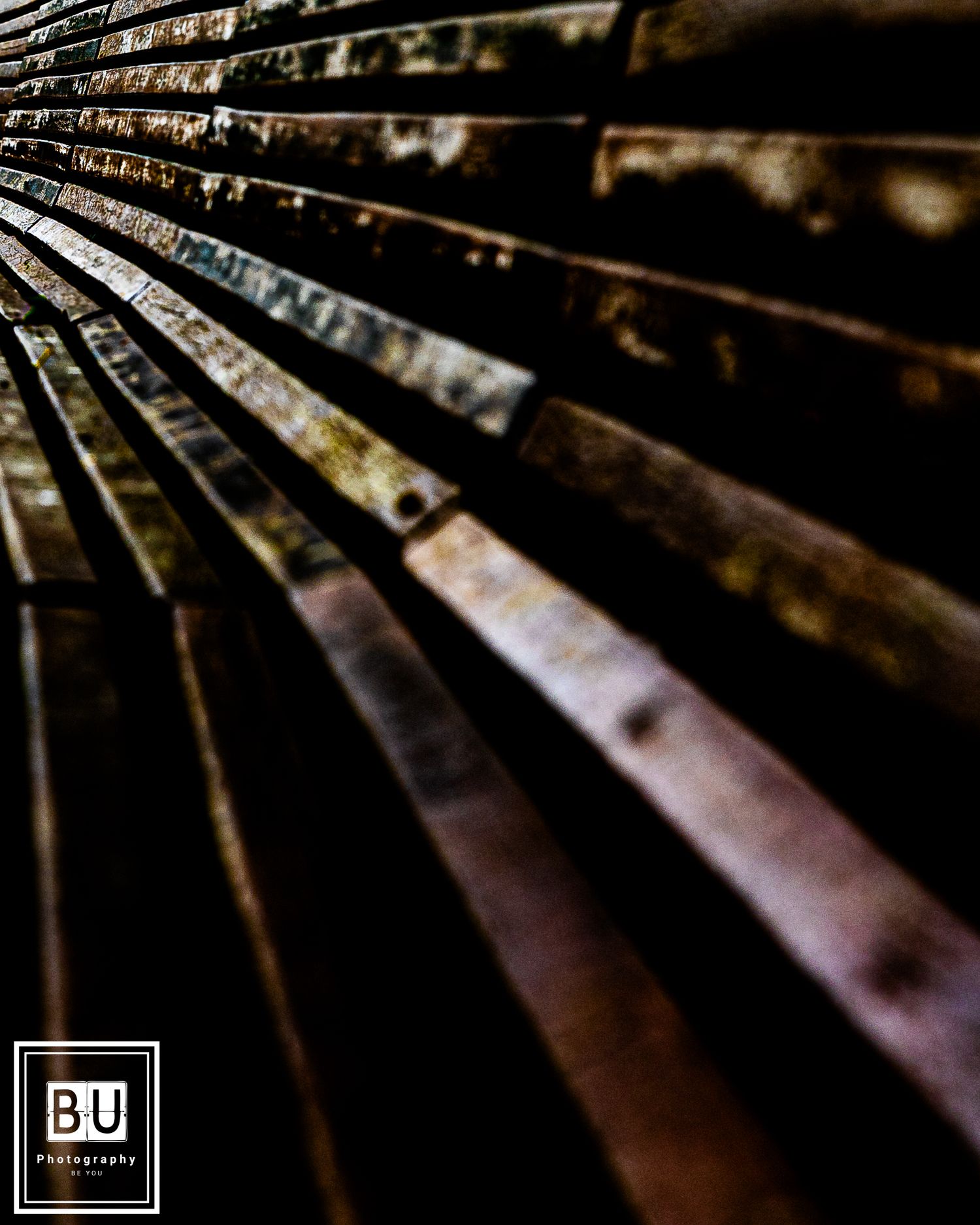 Close-up of weathered wooden bench slats with distressed texture and lighting effects creating depth and shadow.