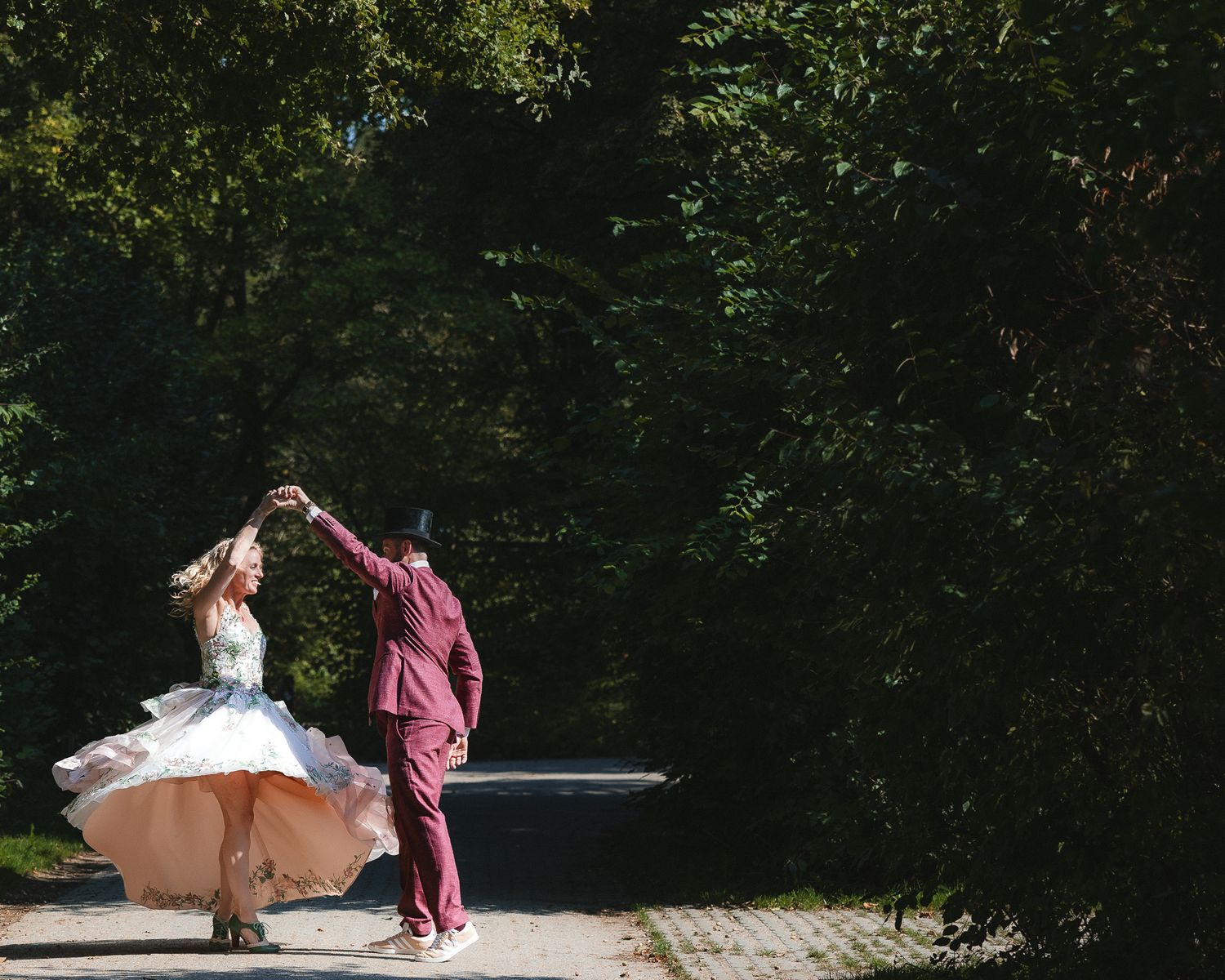 A couple dancing together on a forest path, with the bride's white dress twirling gracefully in motion.