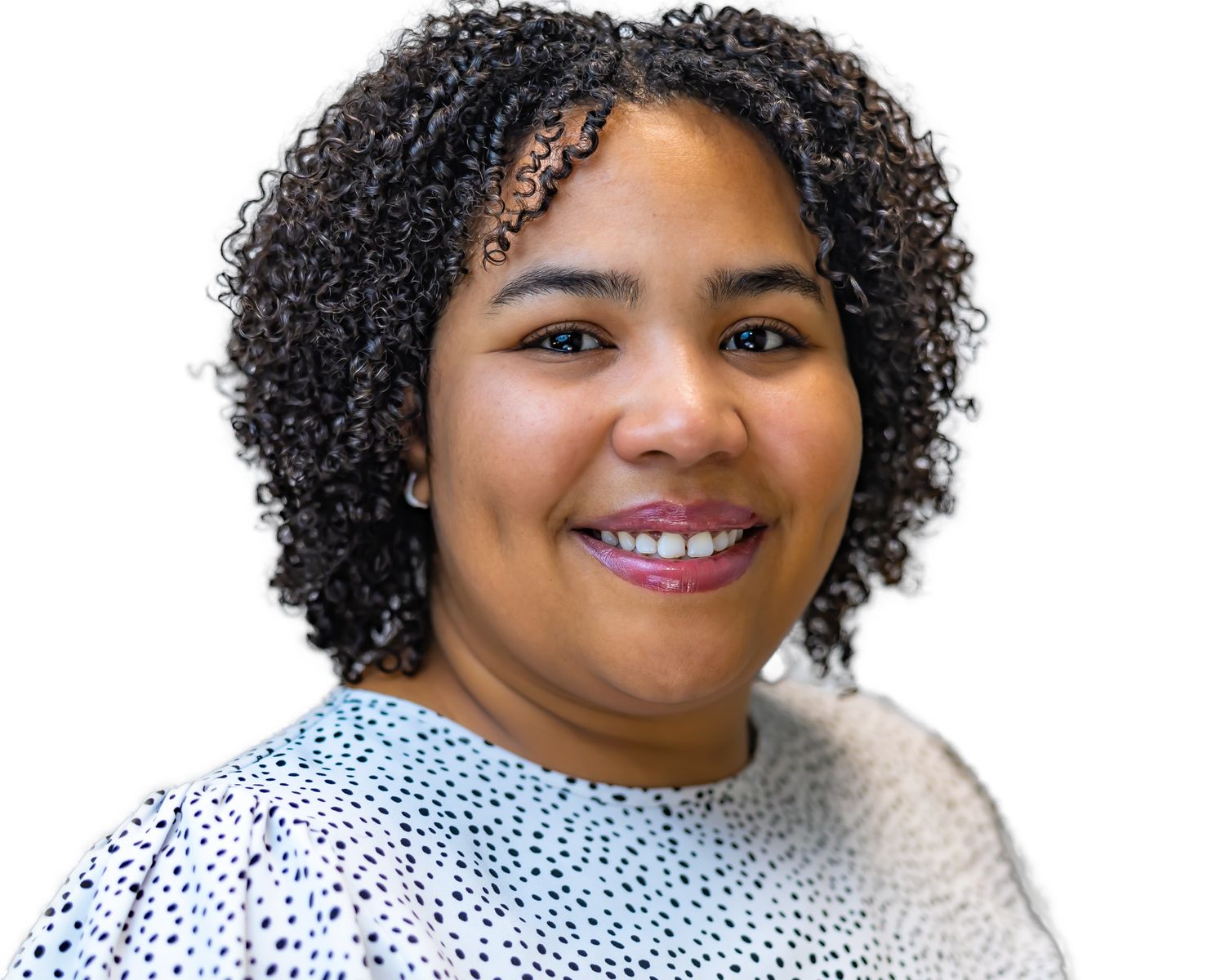 Professional headshot of someone with natural curly hair wearing a blue and white patterned top against white background.