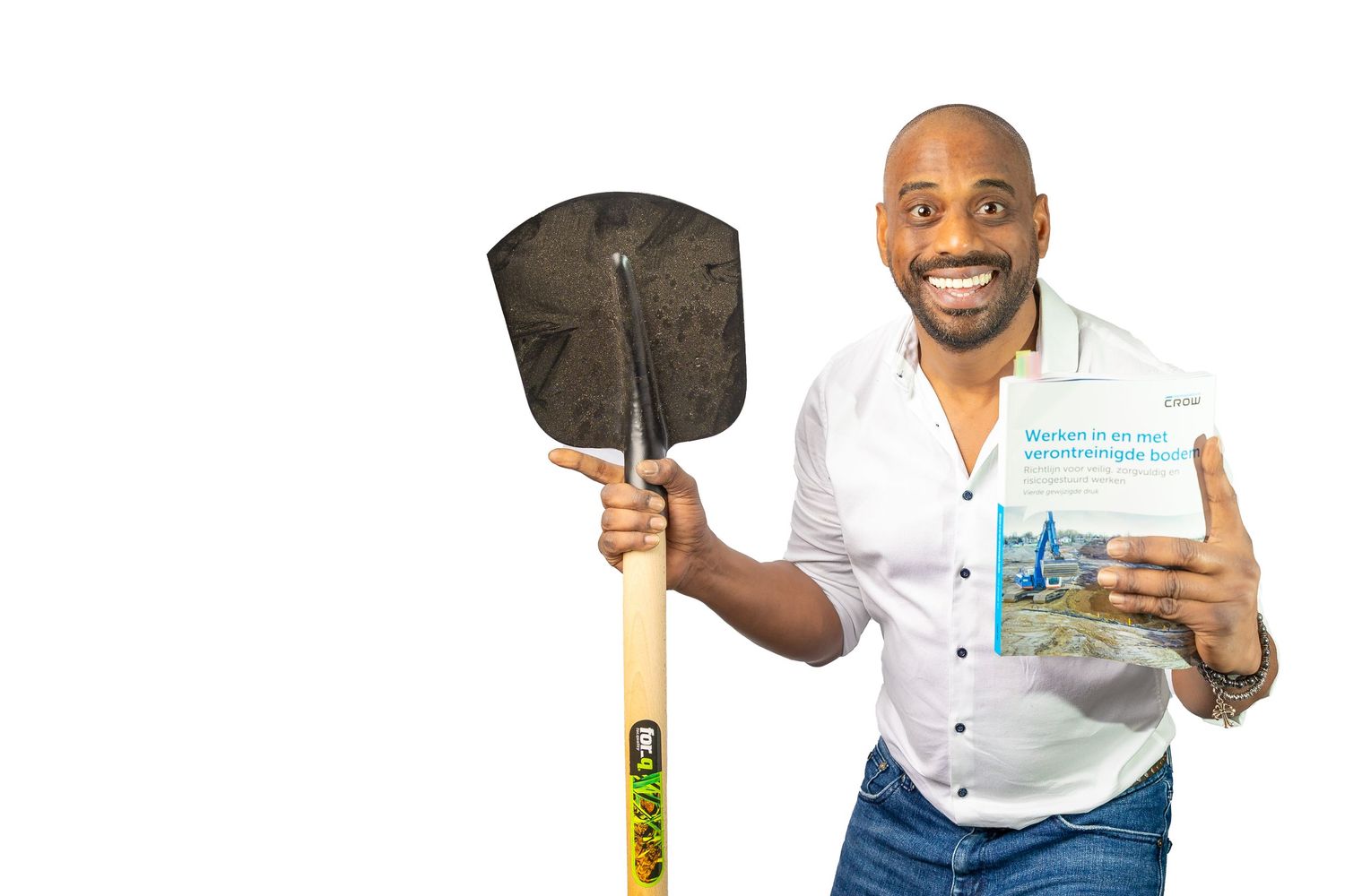 A person in a white shirt holds a gardening shovel and a book about preparing garden soil.