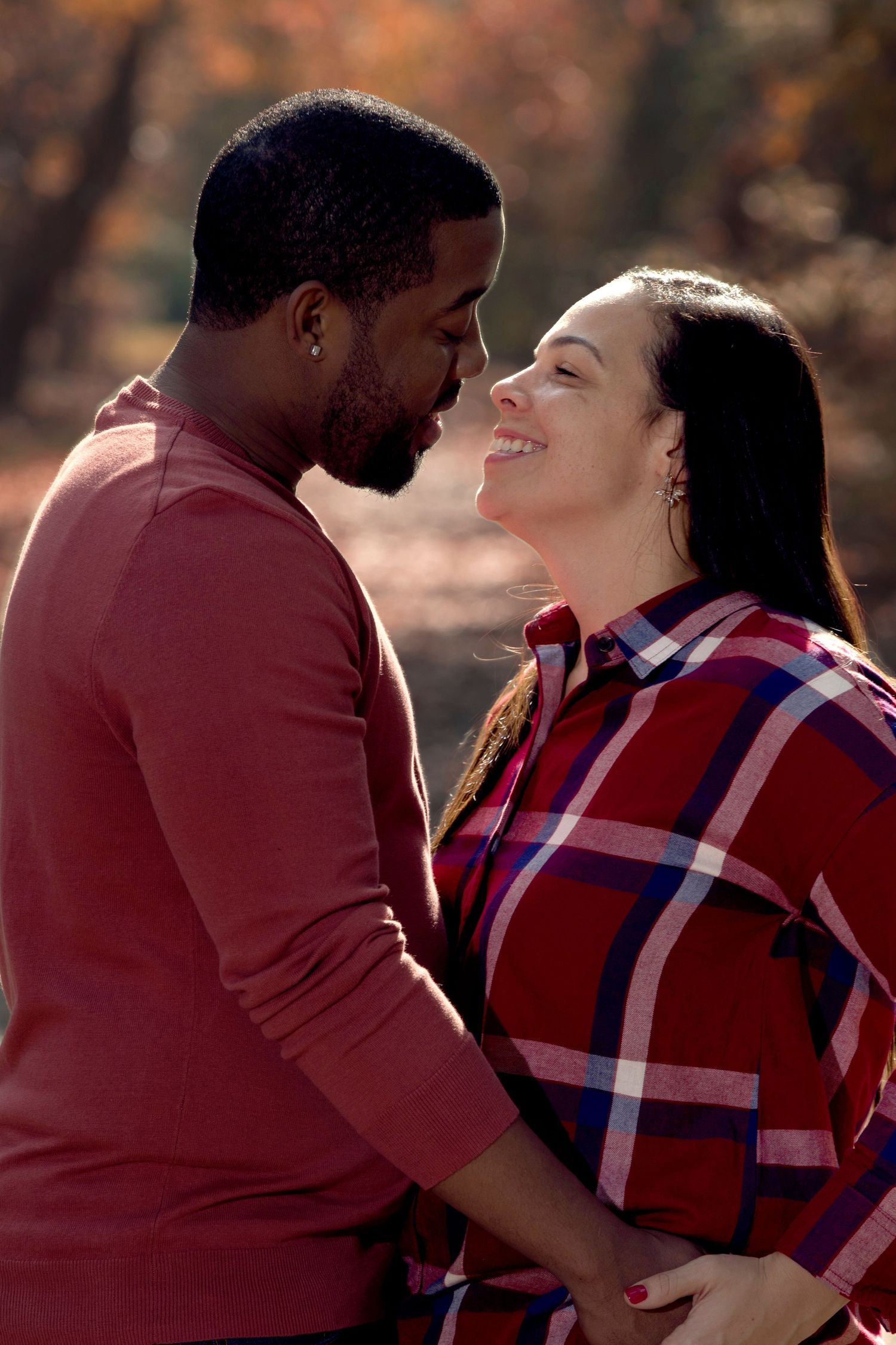 A couple in warm sweaters share a tender romantic moment outdoors during autumn.