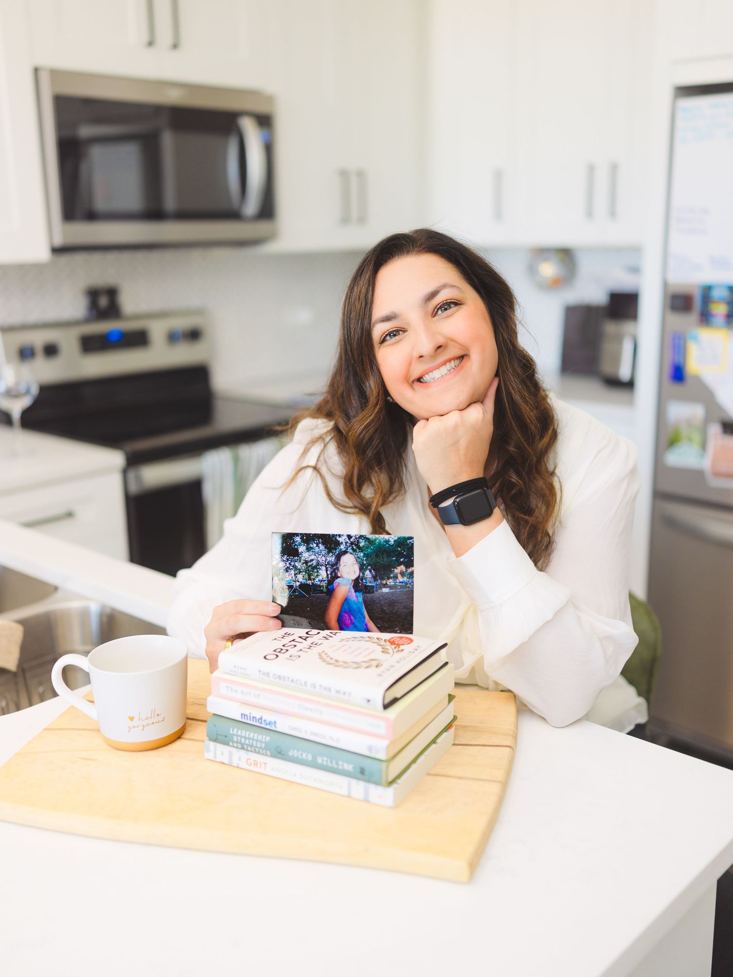A person sits at a white desk with books and a laptop, showing different poses while studying in a modern kitchen.