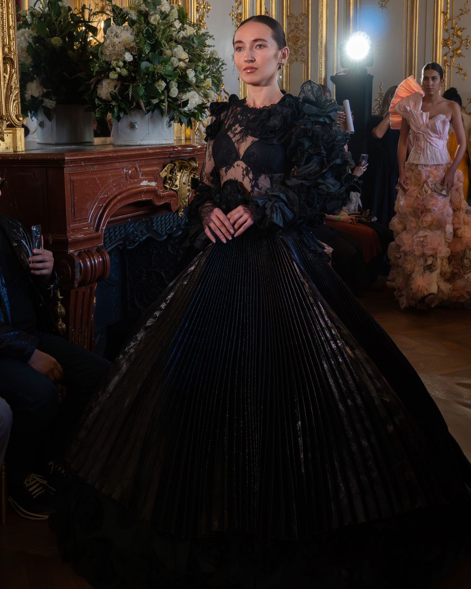 Mannequin portant une robe de bal noire avec des détails à volants dans un hôtel prestigieux à Paris lors de la Paris Fashion Week.