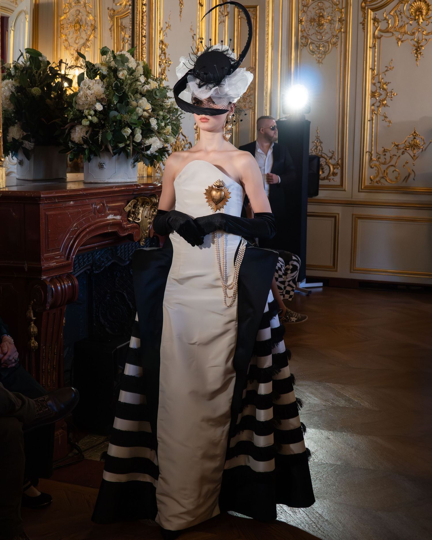 Robe bustier élégante couleur crème et chapeau noir spectaculaire sur un défilé de mode pendant la Paris Fashion Week.