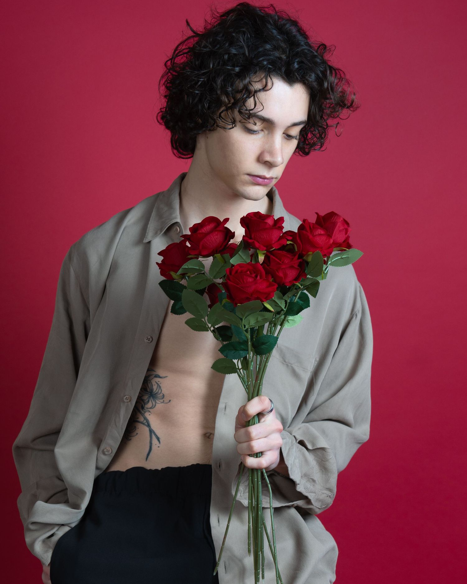 Photo de mode artistique avec veste beige et roses rouges sur fond cramoisi pour un book modèle lors de la saint Valentin.