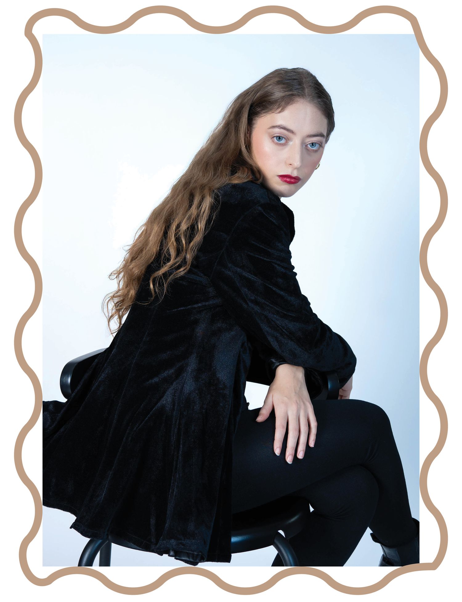 photographie d'un modèle en manteau de velours noir pose sur fond blanc avec bordure de cadre décorative pour le magazine l'Attirance.