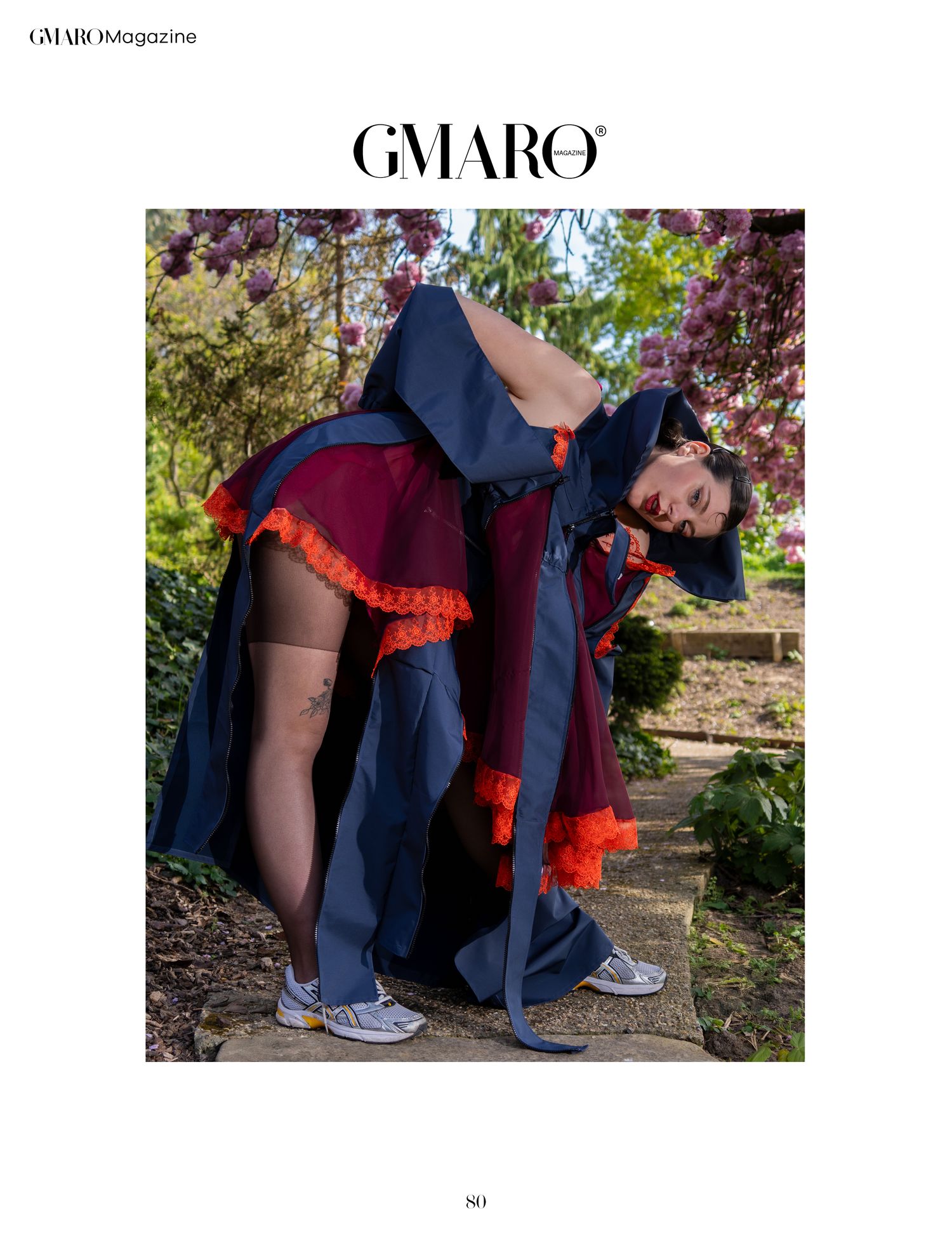 Photographie pour le magazine de mode GMARO présentant un mannequin portant une robe bleu marine avec du tule bordeaux sur fond de jardin.