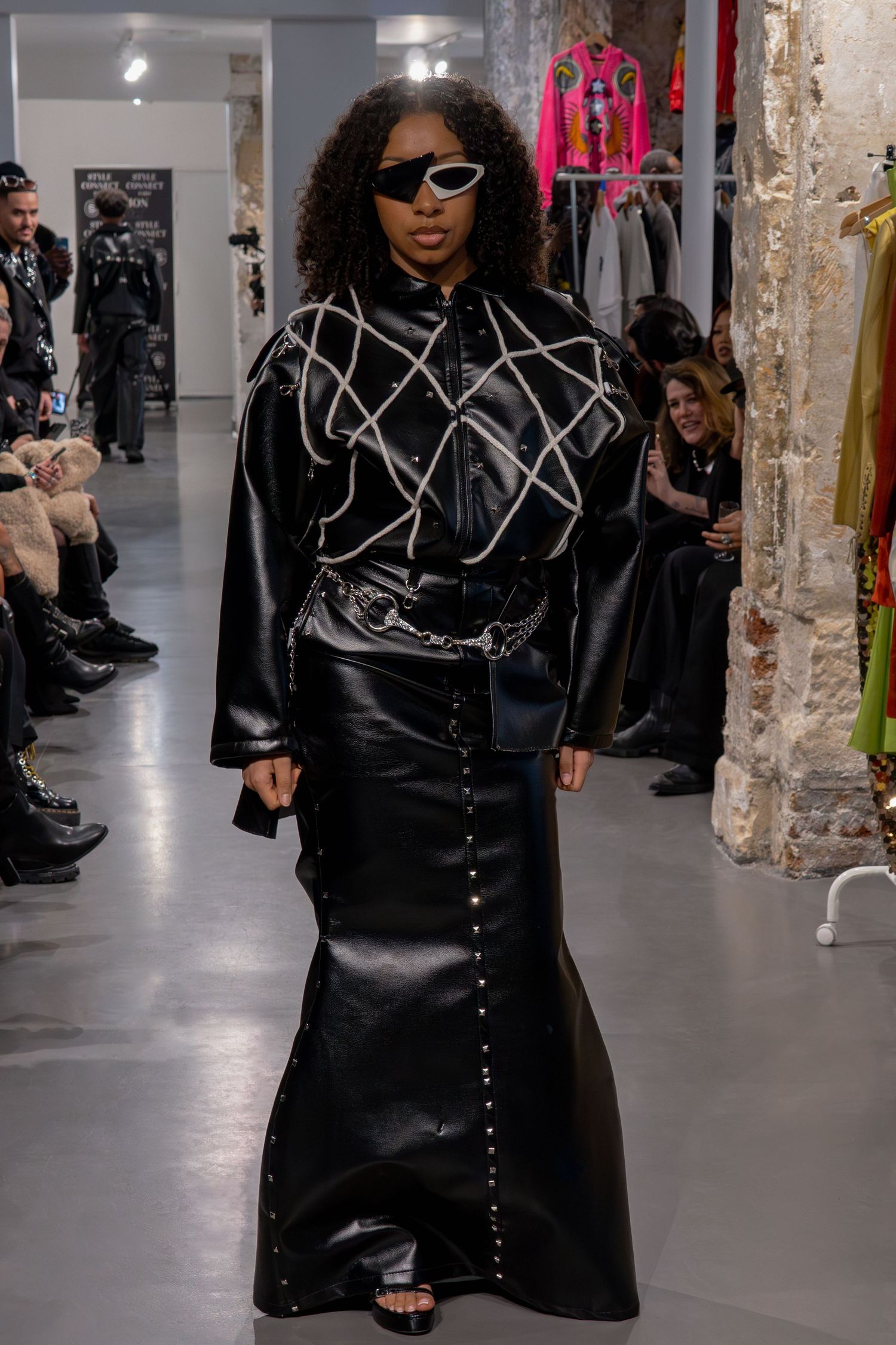 Mannequin en tenue inspirée de Matrix en cuir noir avec motif géométrique et lunettes de soleil sur le podium pour la Paris Fashion Week.