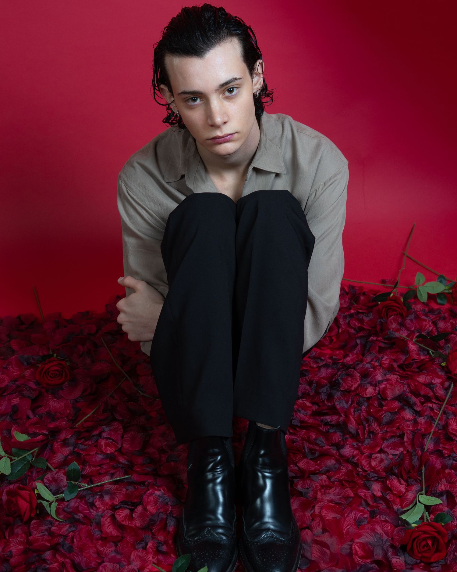 Portrait artistique sur fond rouge avec des bottes noires et des pétales de rose rouges pour un book modèle lors de la st Valentin.