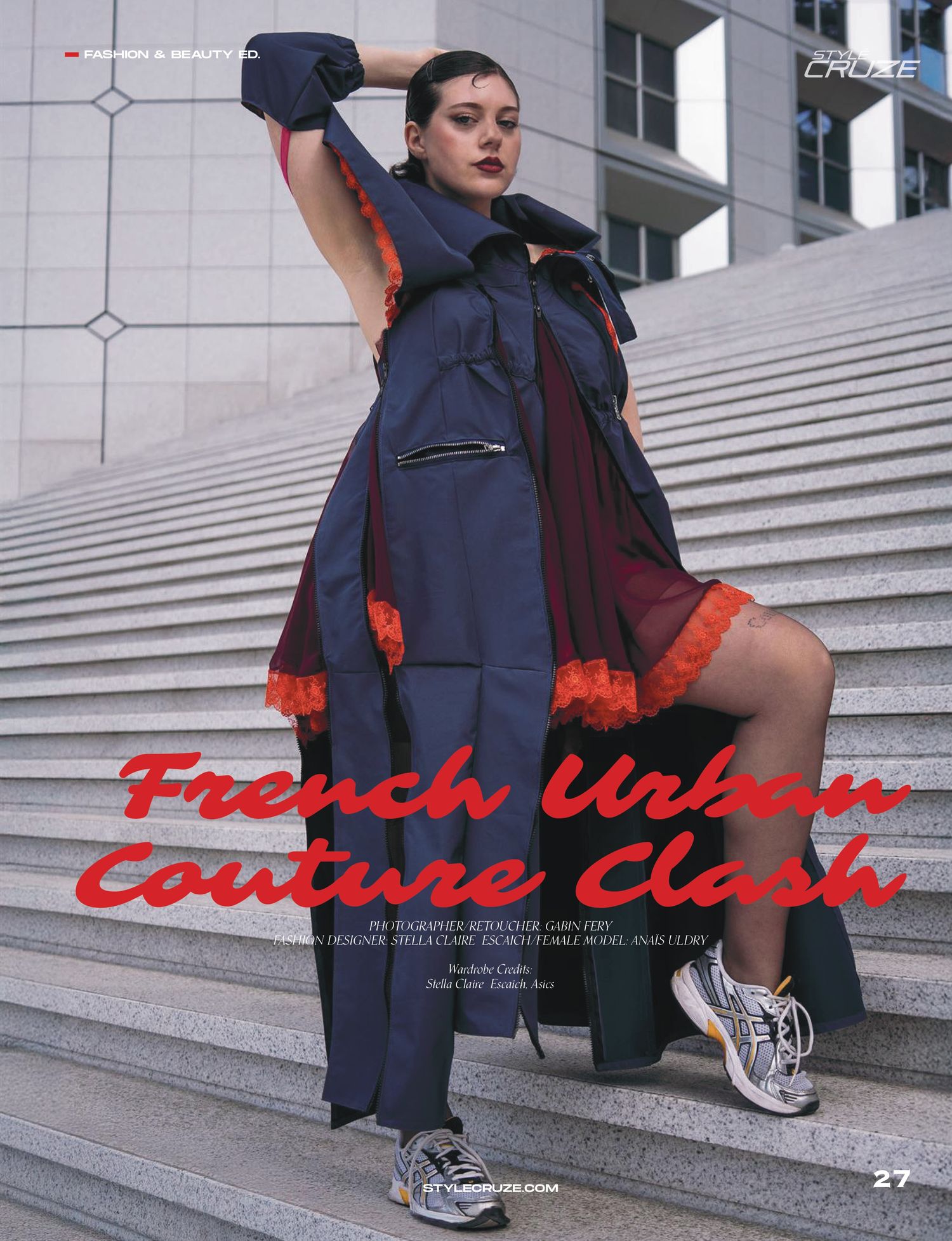 Fashion model wearing navy coat with red trim and chunky sneakers poses on concrete steps for urban couture photo shoot.