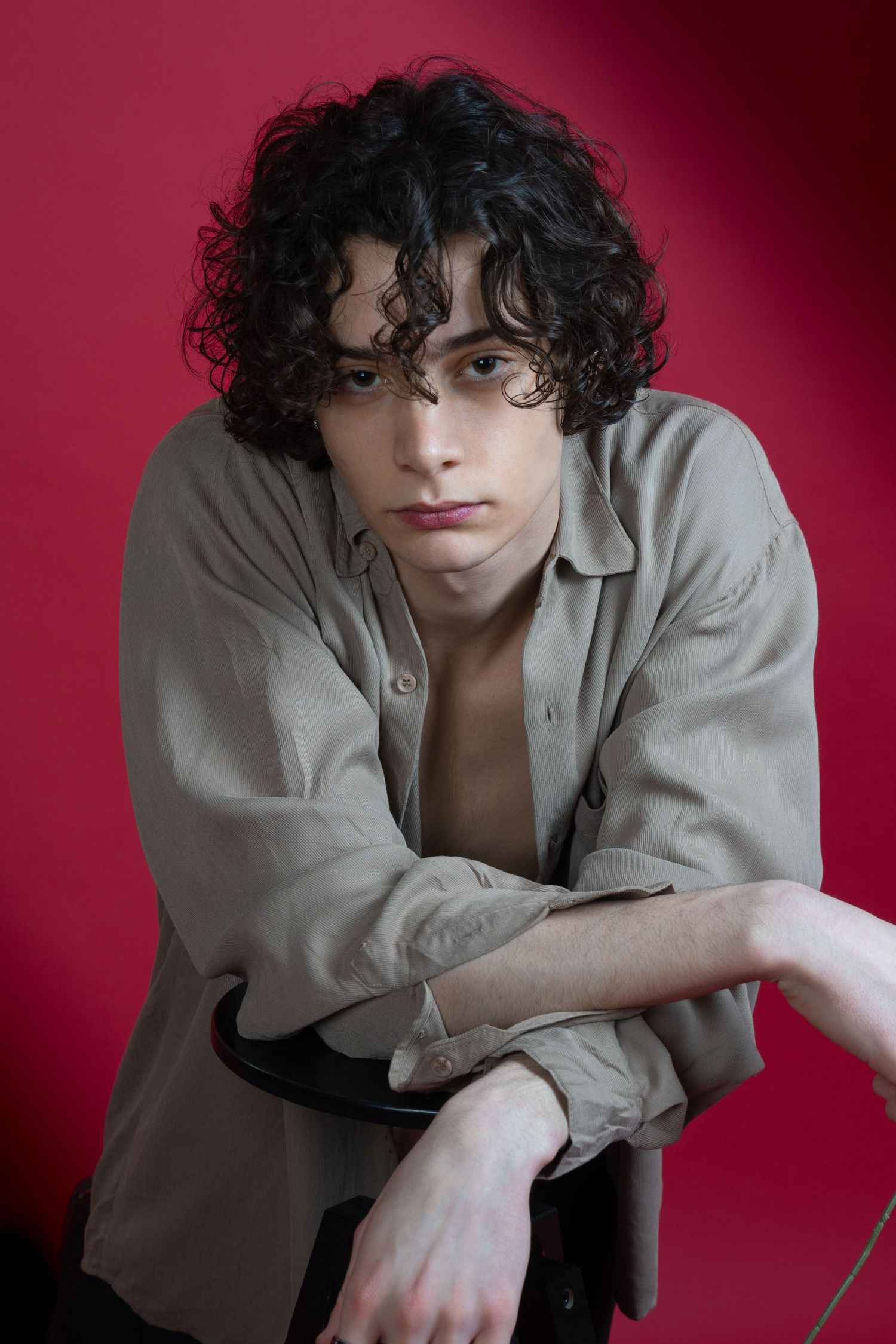Portrait artistique d'un modèle pour un book agence en chemise beige déboutonnée sur fond rouge foncé pour la Saint Valentin.