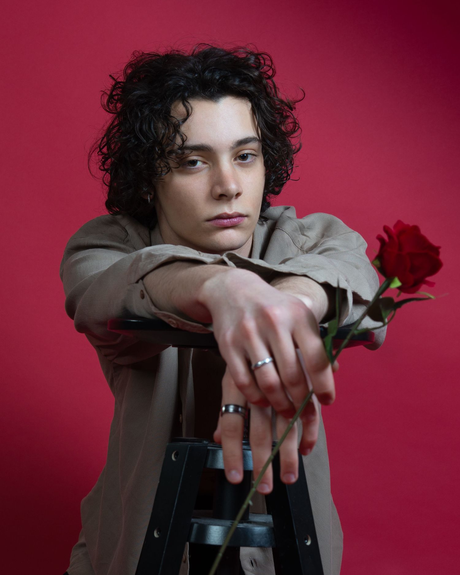 Portrait pensif avec une seule rose rouge sur fond bordeaux pour la saint Valentin.
