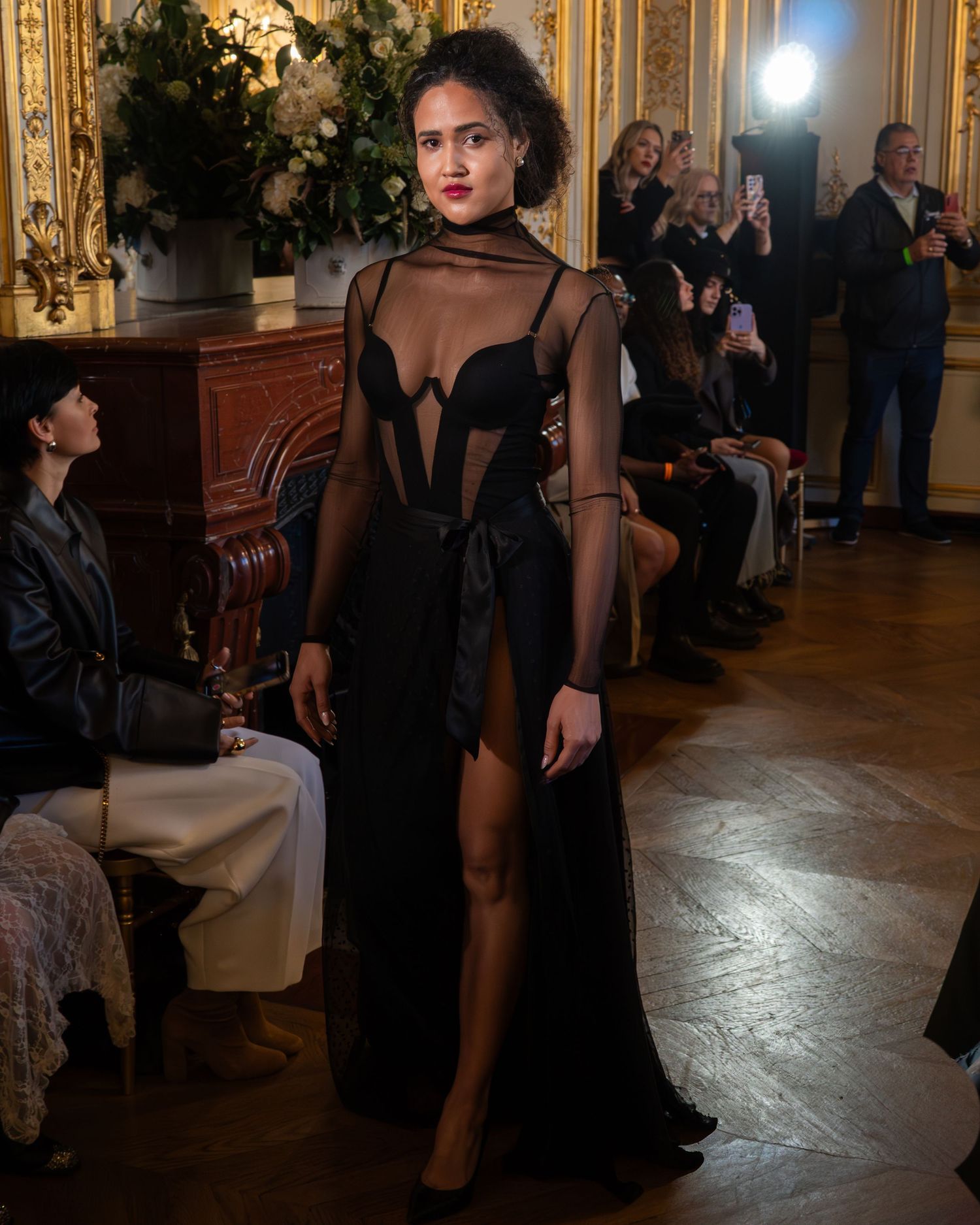 Robe de soirée noire transparente avec une fente haute spectaculaire présentée sur le podium luxueux lors de la Paris Fashion Week.