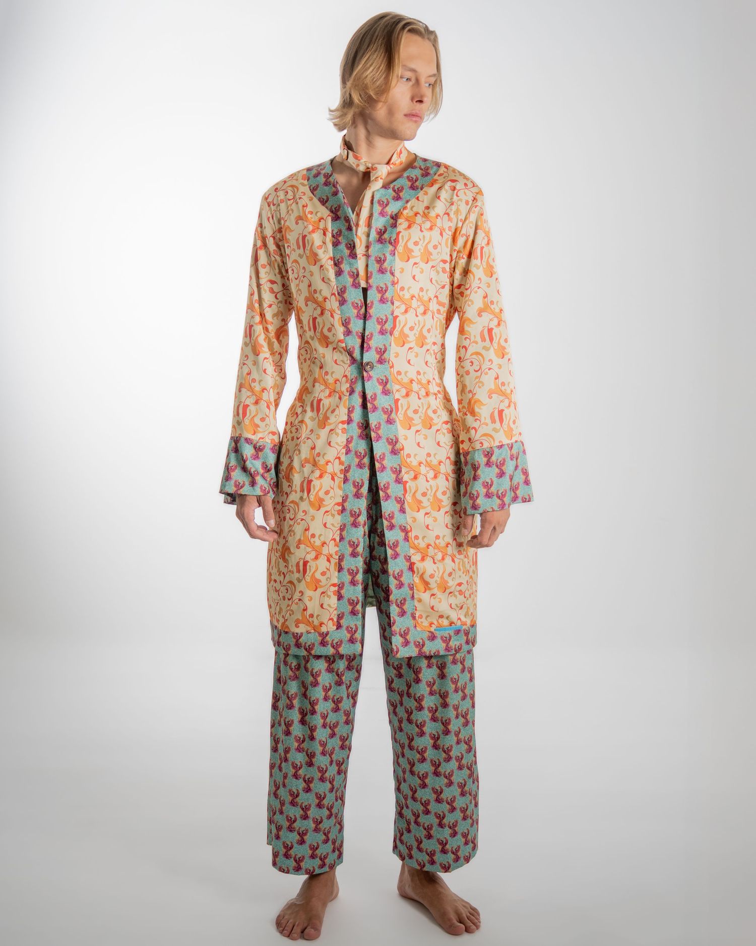 Person wearing colorful floral print loungewear with orange and blue patterns in a relaxed studio setting.