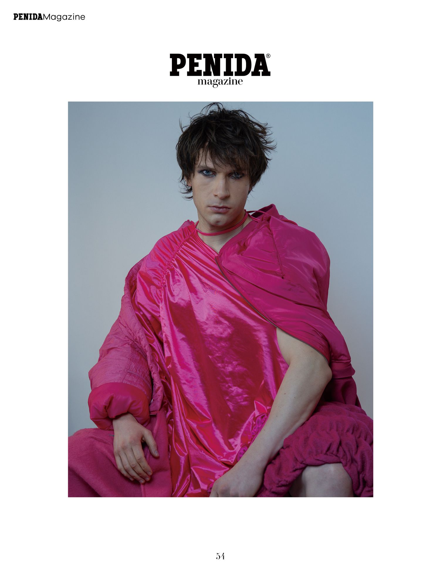 Photo éditoriale de mode montrant un mannequin vêtu d'un tissu drapé rose vif surdimensionné sur fond gris pour le magazine PENIDA.