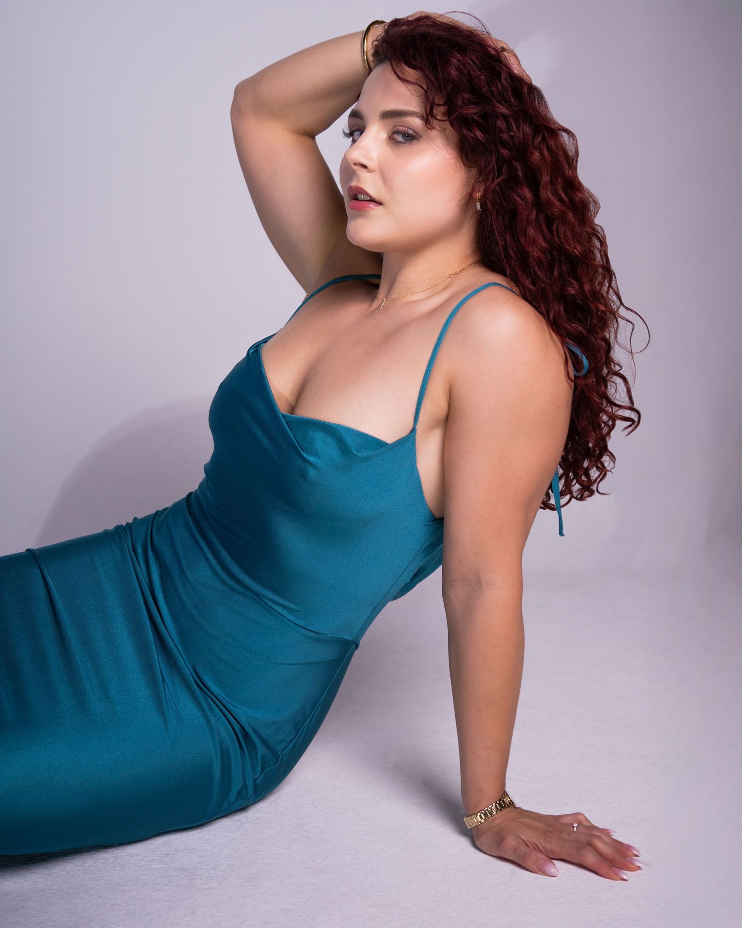 Person in teal dress poses gracefully in a series of artistic studio photos with soft lighting and purple backdrop.