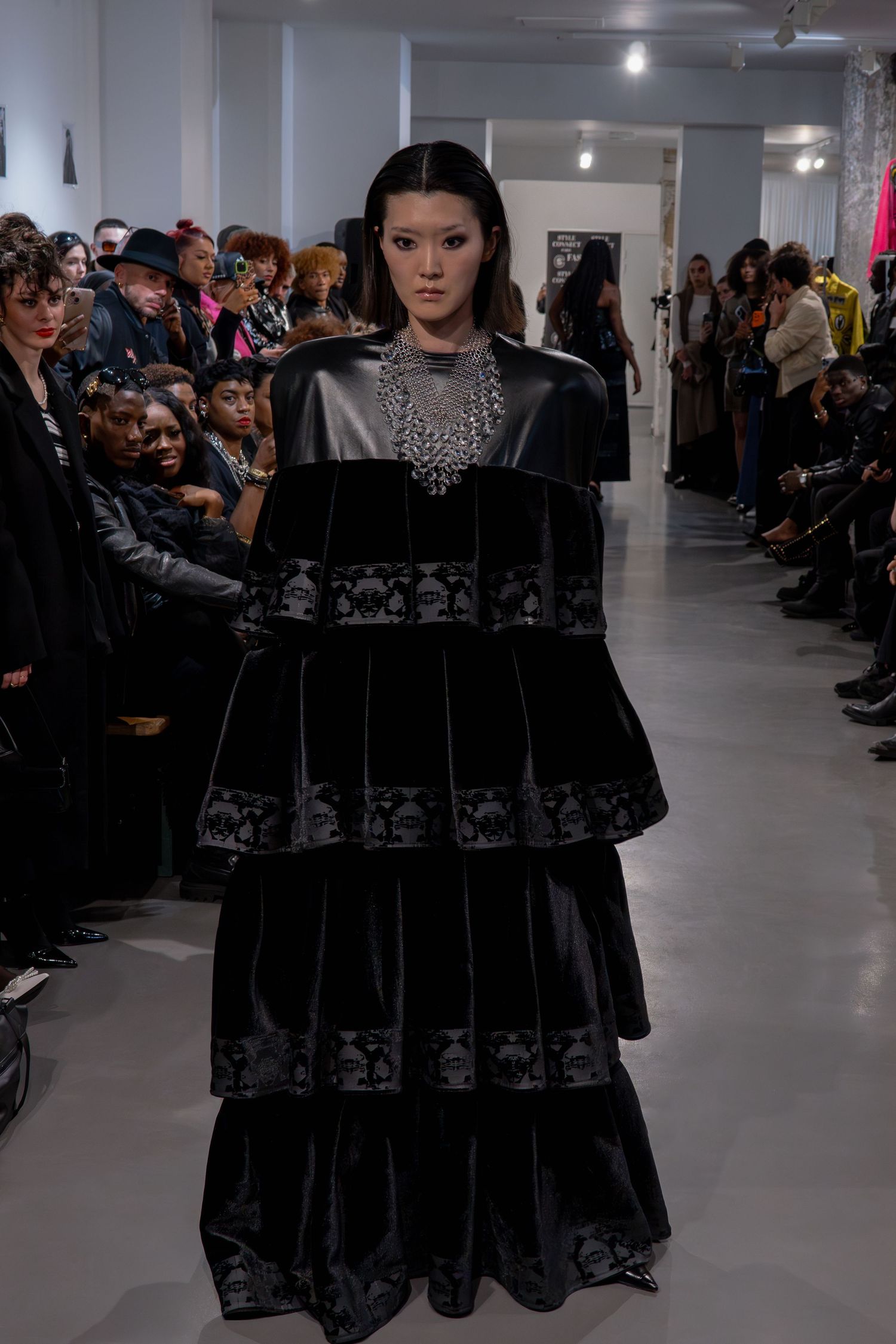 Robe noire  à plusieurs niveaux avec détails de corsage métalliques présentée lors d'un défilé de mode pour la Paris Fashion Week.