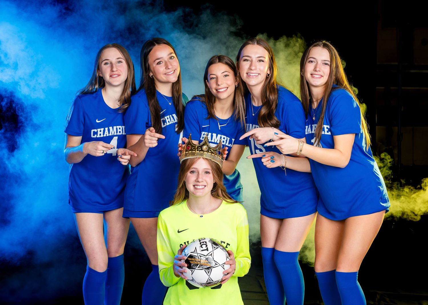 High school soccer team poses in blue uniforms with colored smoke effects in dramatic sports photo.