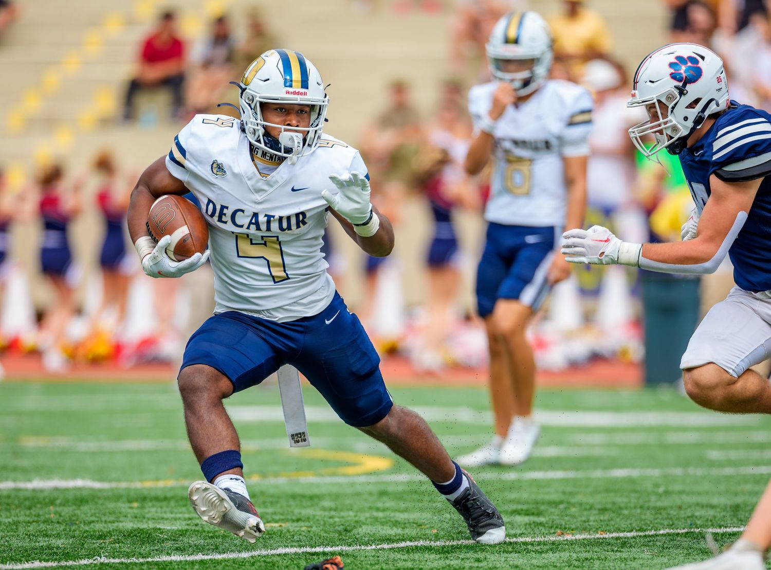 Football player in blue and white uniform running with the ball during a game.