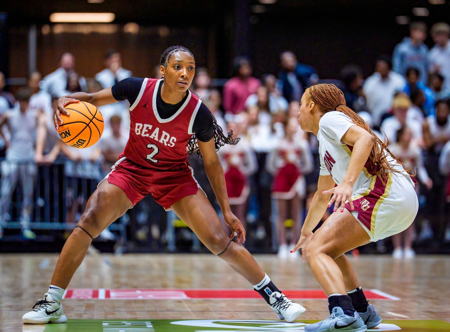 Two basketball players face off during an intense defensive matchup in a collegiate women's basketball game.