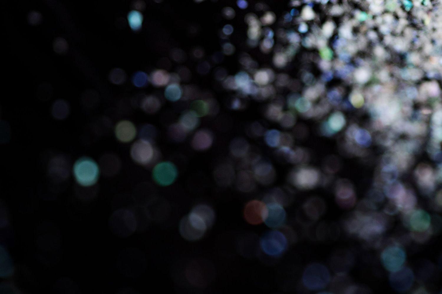Abstract bokeh background with colorful blurred light circles on dark black backdrop for festive design.