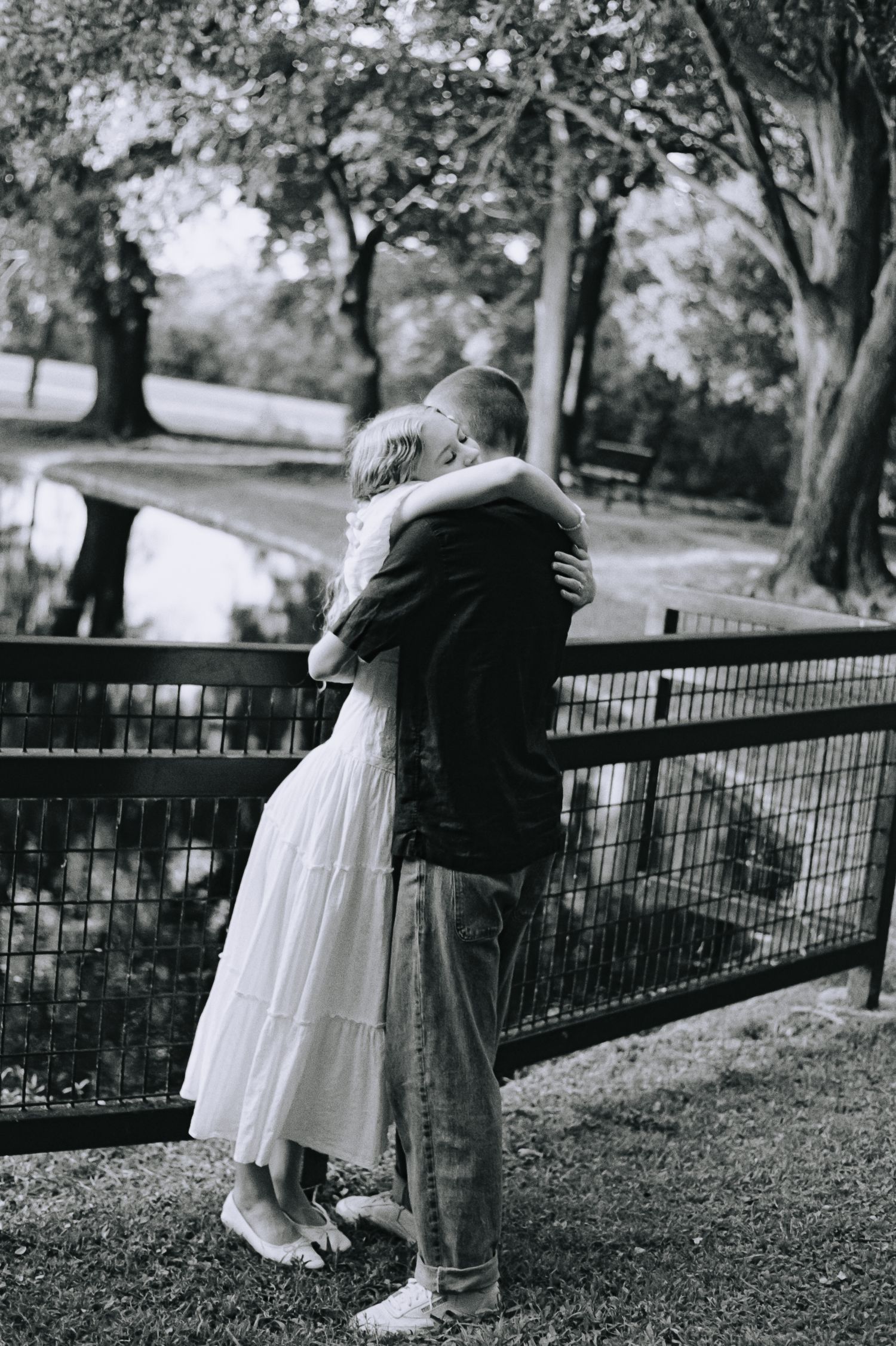 Black and white series of romantic vintage photographs showing a couple embracing by a park railing.