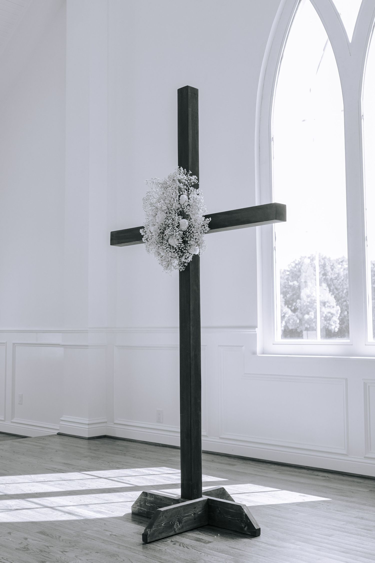 A series of minimalist white interior spaces with black structural beams and natural light streaming through arched windows.
