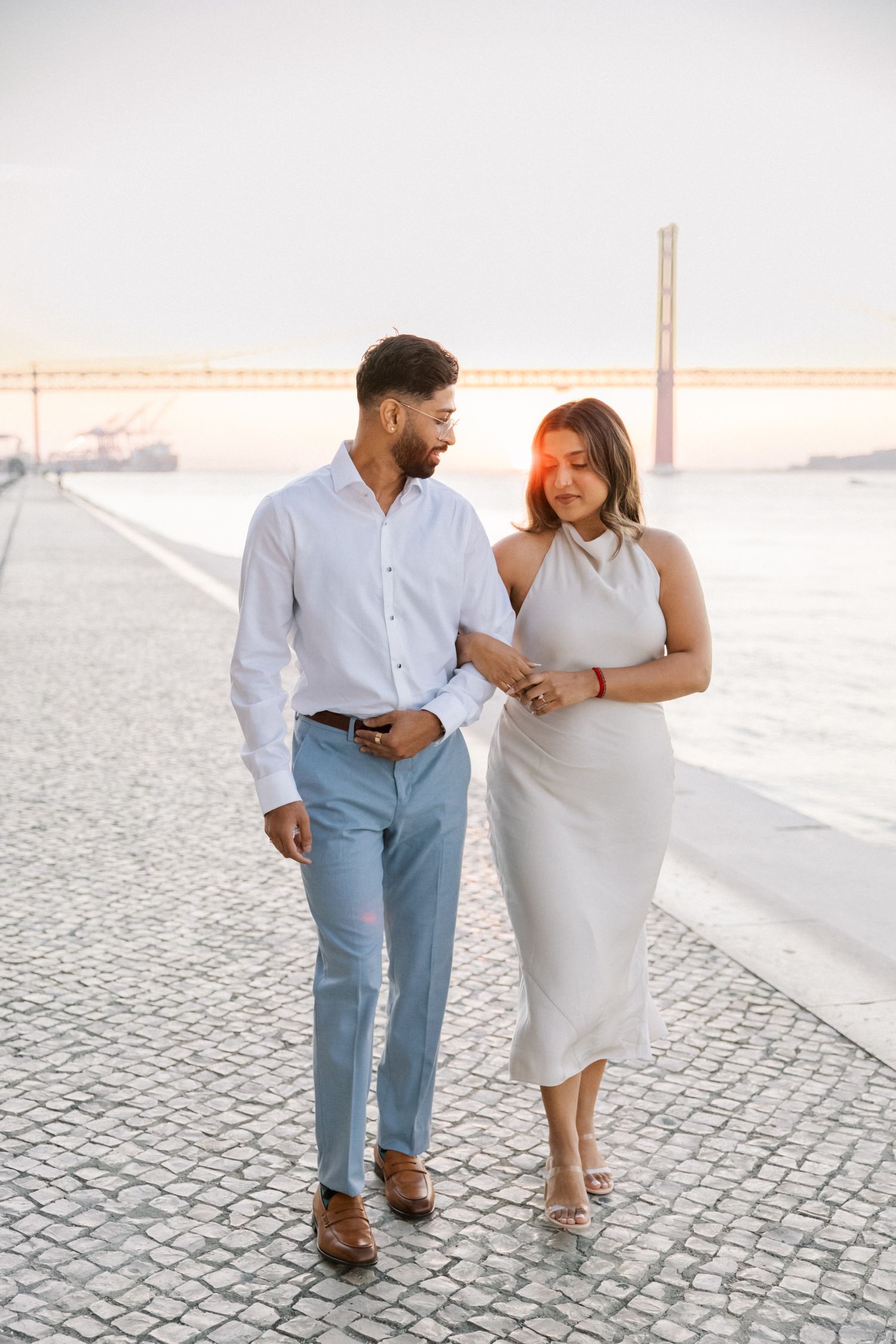 Cinematic sunrise engagement session at MAAT Lisbon — couple walking by the river, captured by destination wedding photographer in Portugal
