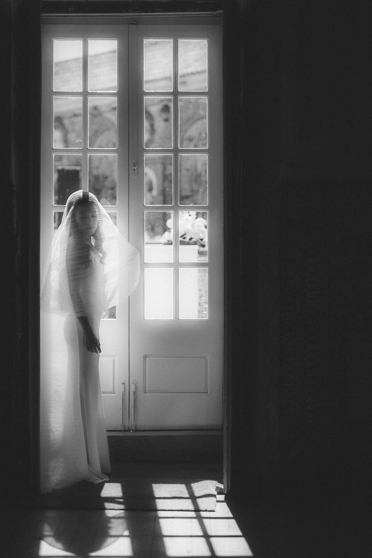 Asian bride in minimalist wedding gown, standing in soft shadowed light at Palácio de Fronteira by a Lisbon wedding photographer