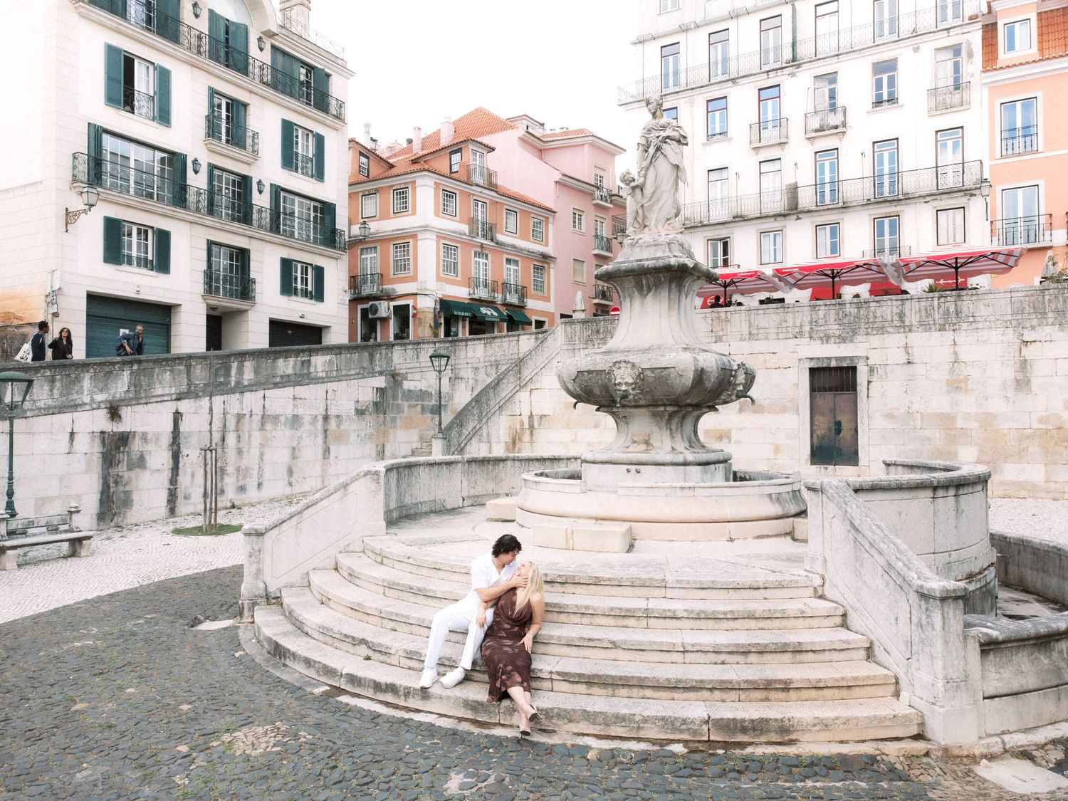 Destination wedding couple sitting together in a historic Lisbon square during their pre wedding session in Portugal