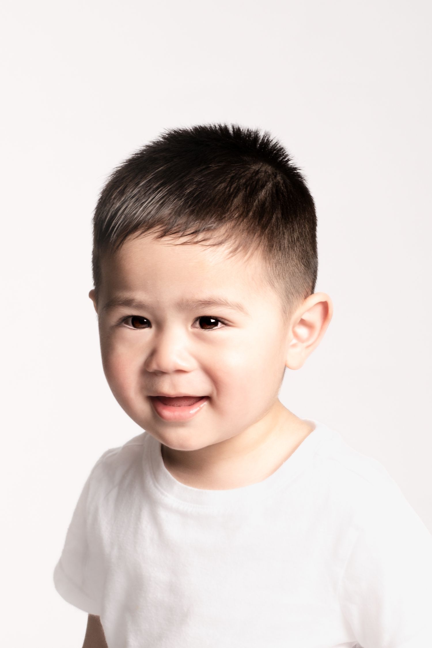 Portrait series of young child in white t-shirt showing happy expressions against white background.