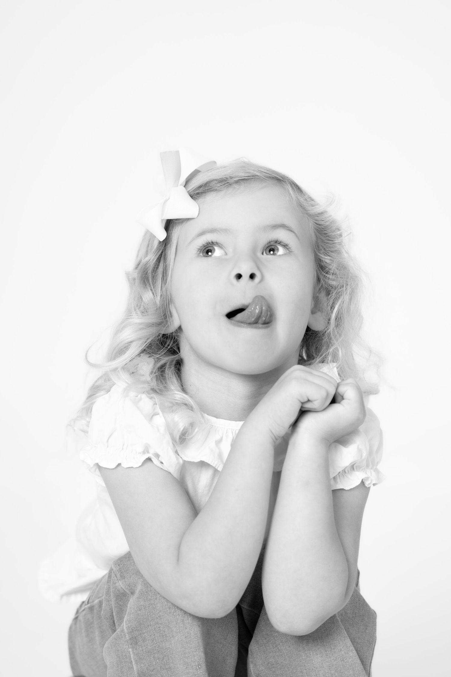 A series of four black and white portraits showing a child making playful expressions and poses.