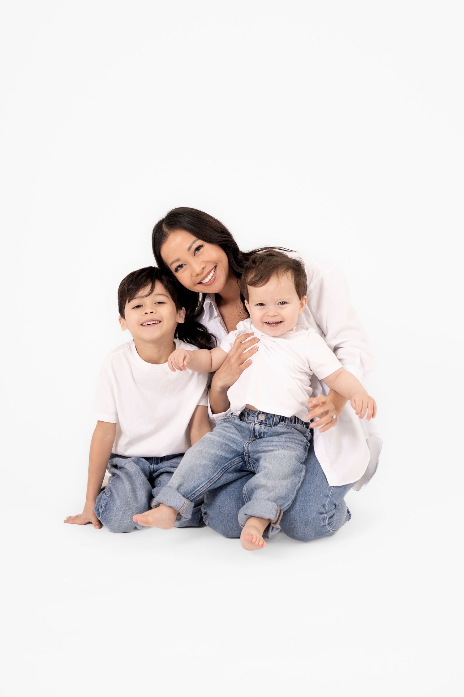 Family members in casual white tops and jeans relaxing together on white background.