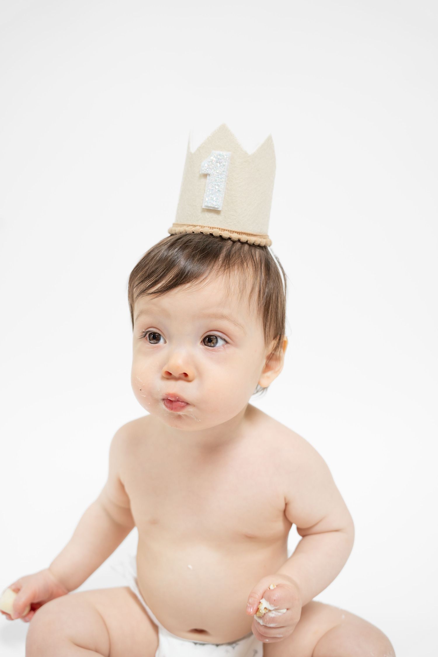Baby in paper crown showing various expressions during studio photoshoot.