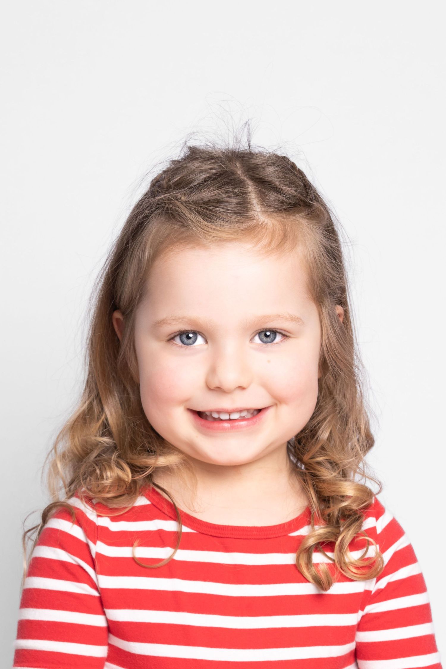 A child in a red and white striped shirt smiles warmly in a series of connected portrait photos.